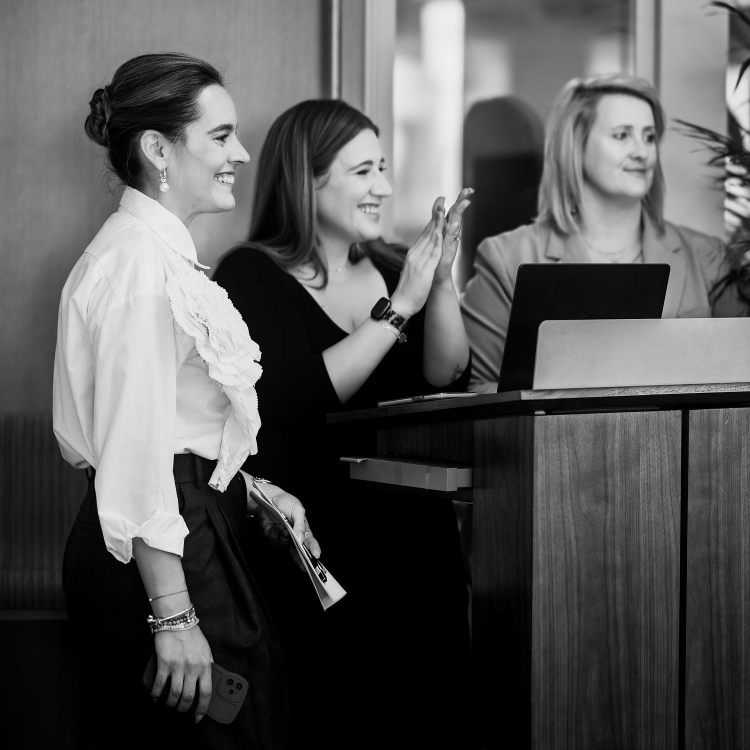 Professional team sharing an enthusiastic moment at a business podium.