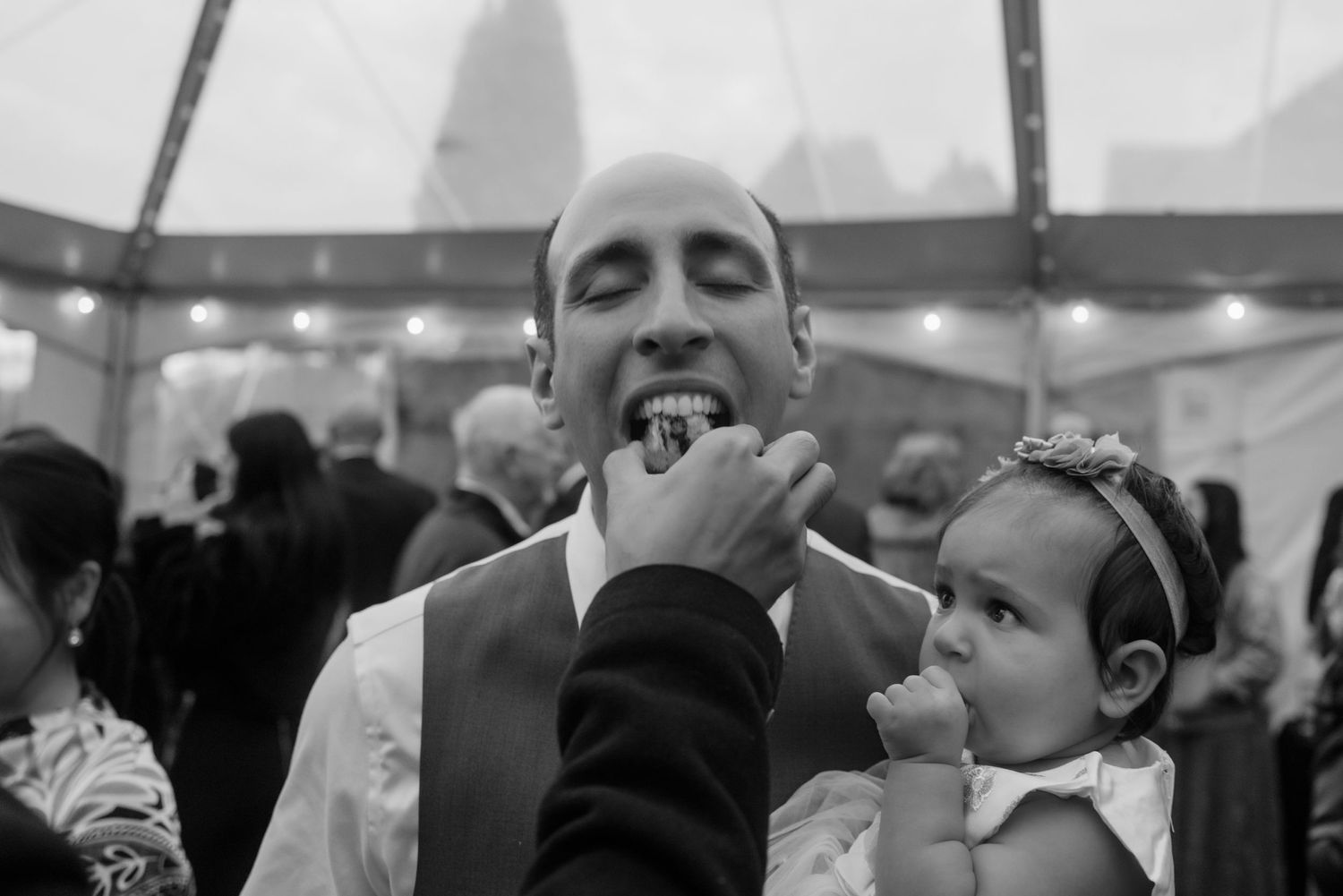 Candid black and white moment of joy and laughter at wedding reception.