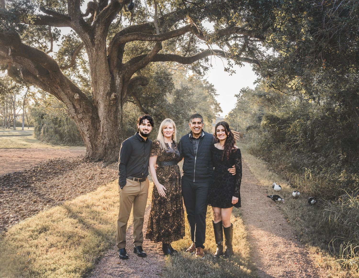A group of people walking together on a dirt path surrounded by trees in natural outdoor setting.  Missouri City Family Photographer