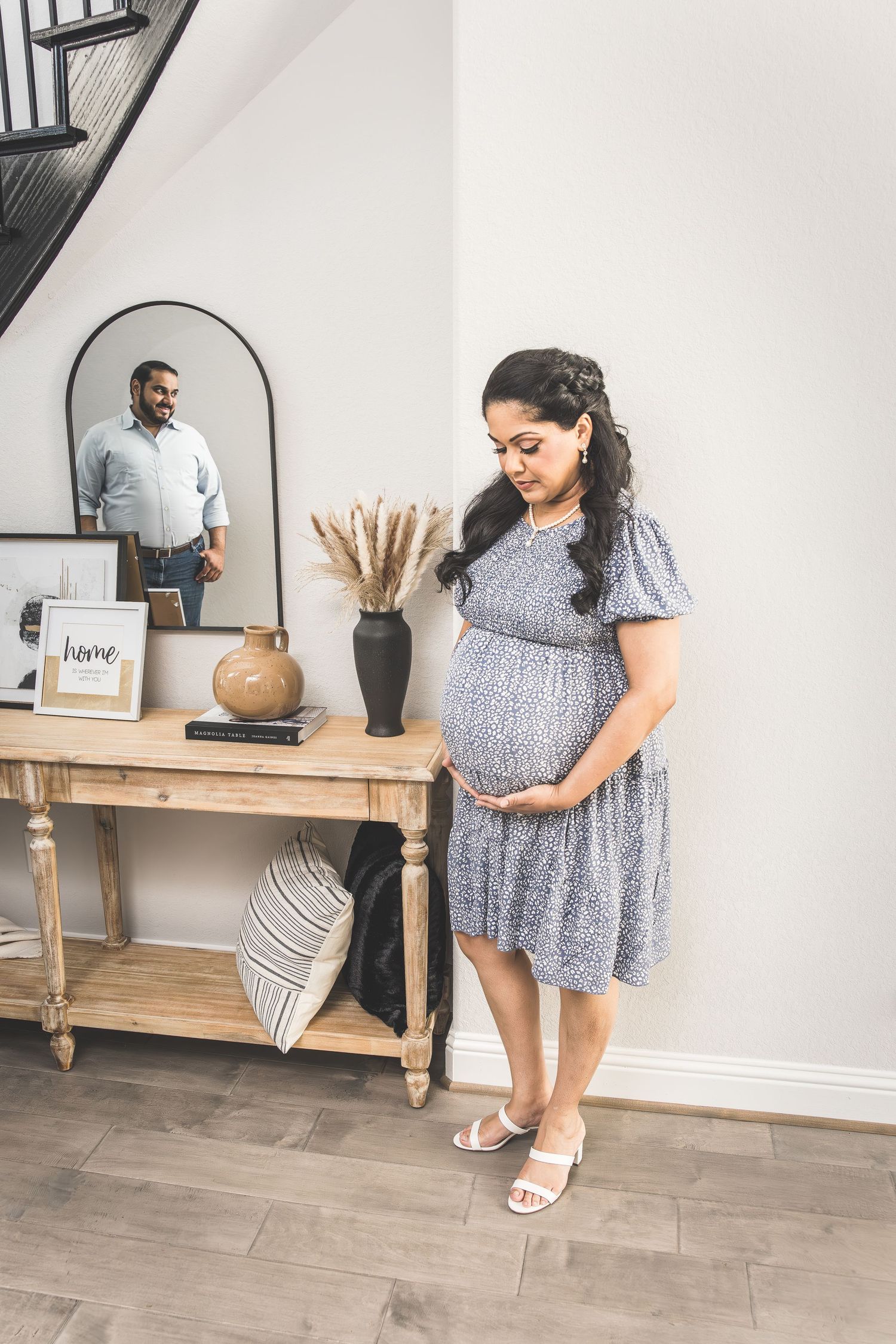 Woman in polka dot dress shows off summer fashion styling with sandals and home decor in modern interior setting.