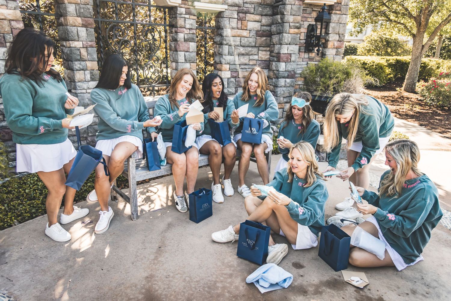 A group of students sitting outdoors with backpacks and laptops while studying together on a sunny college campus.  Pearland Family Photogra