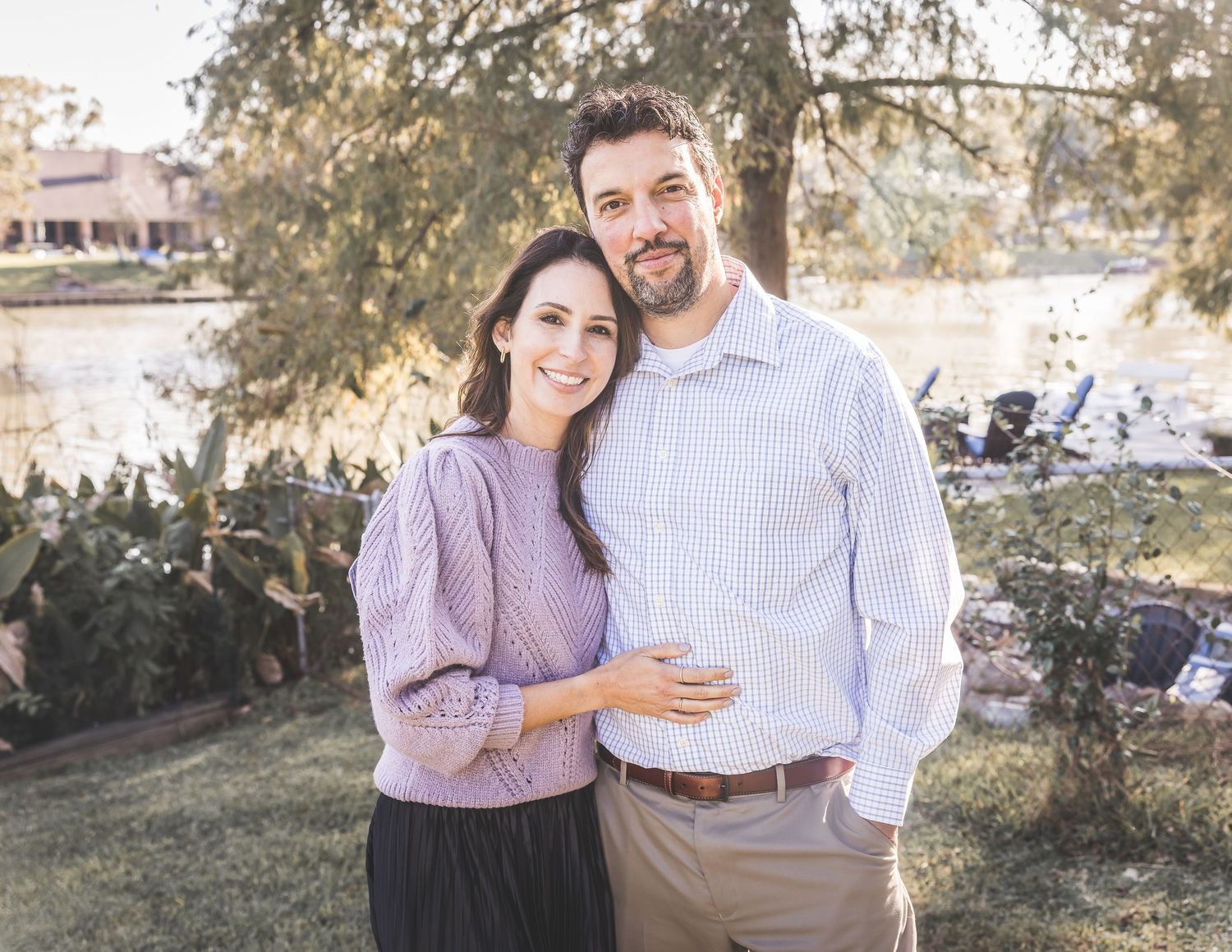 A couple in coordinating lavender and white outfits embrace outdoors during a romantic photoshoot in natural lighting.  Pearland Family Phot