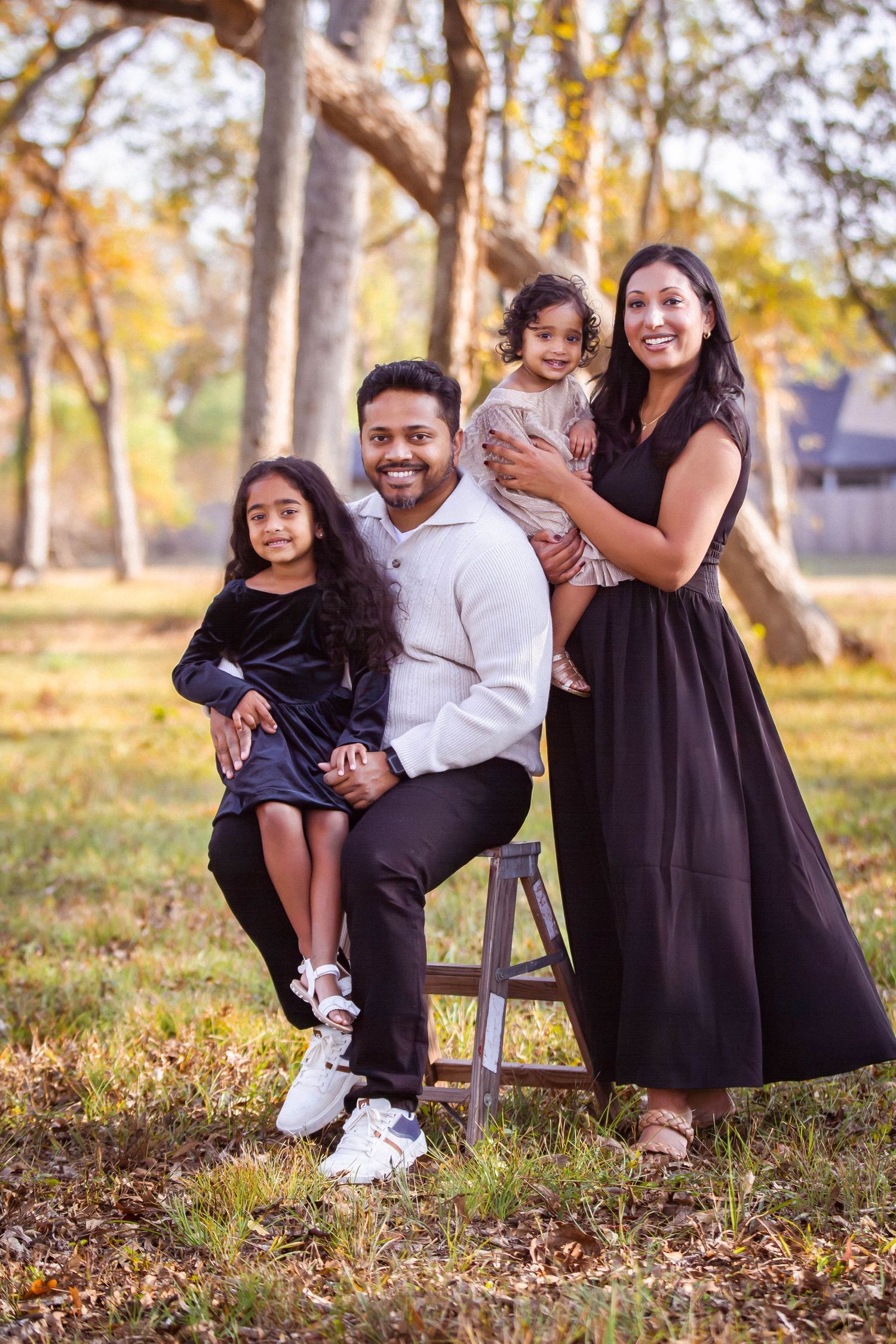 Family wearing coordinated black and white outfits poses together on autumn grass during outdoor photo session.  Missouri City Family Photog