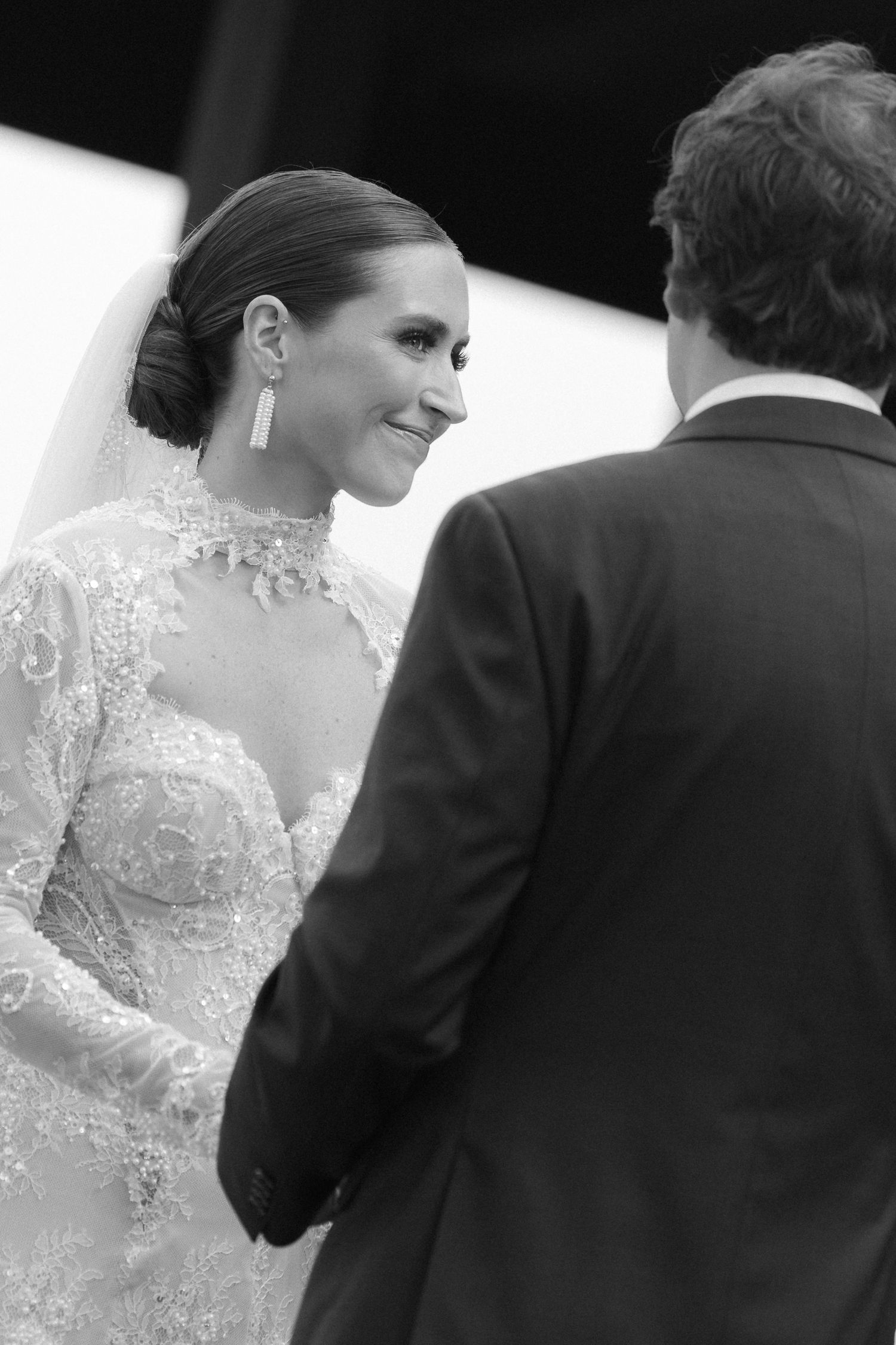 A couple in formal wedding attire photographed from behind during an intimate black and white moment.