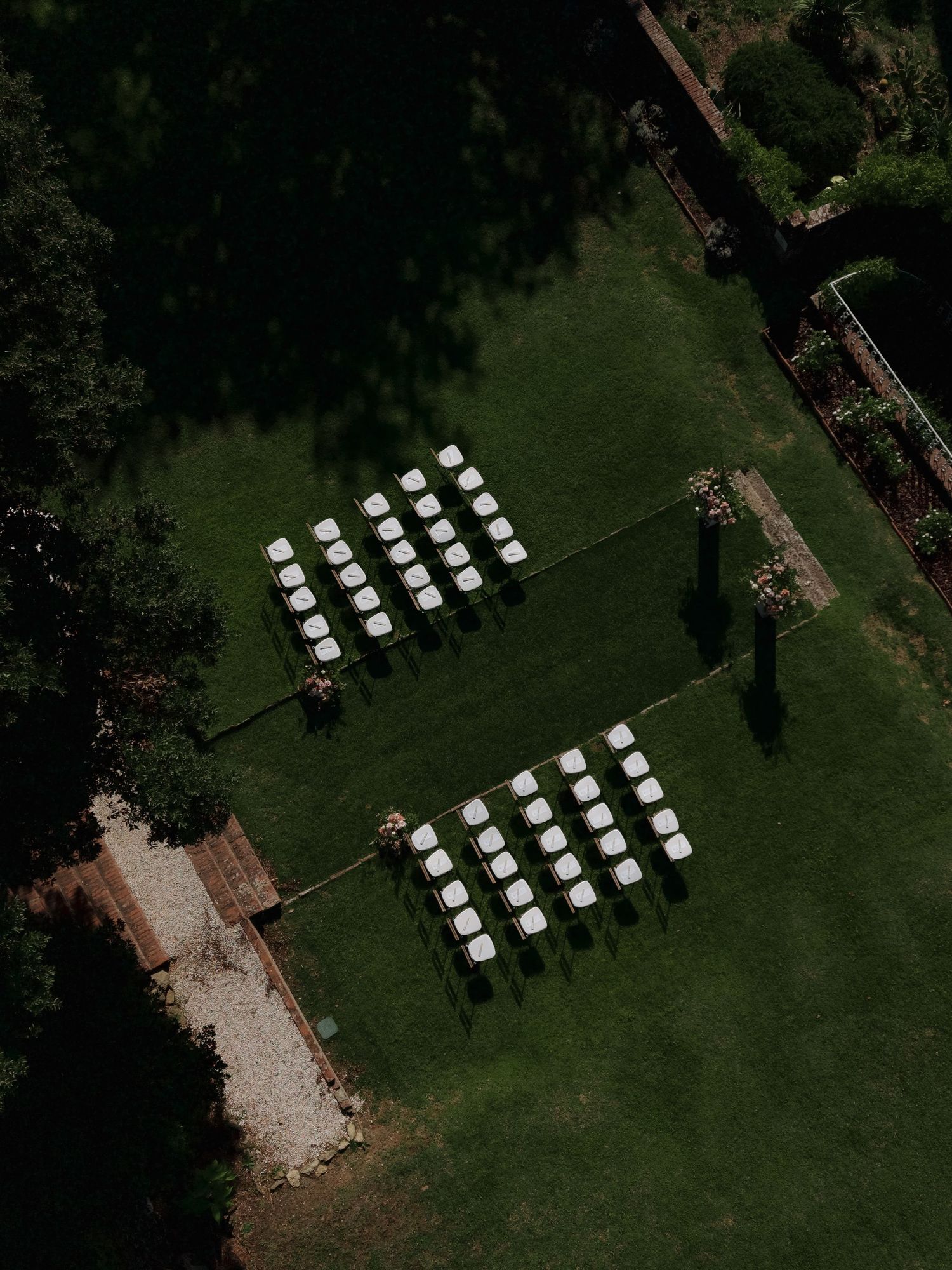 Aerial view of white chairs arranged in rows on green lawn for an outdoor wedding ceremony.