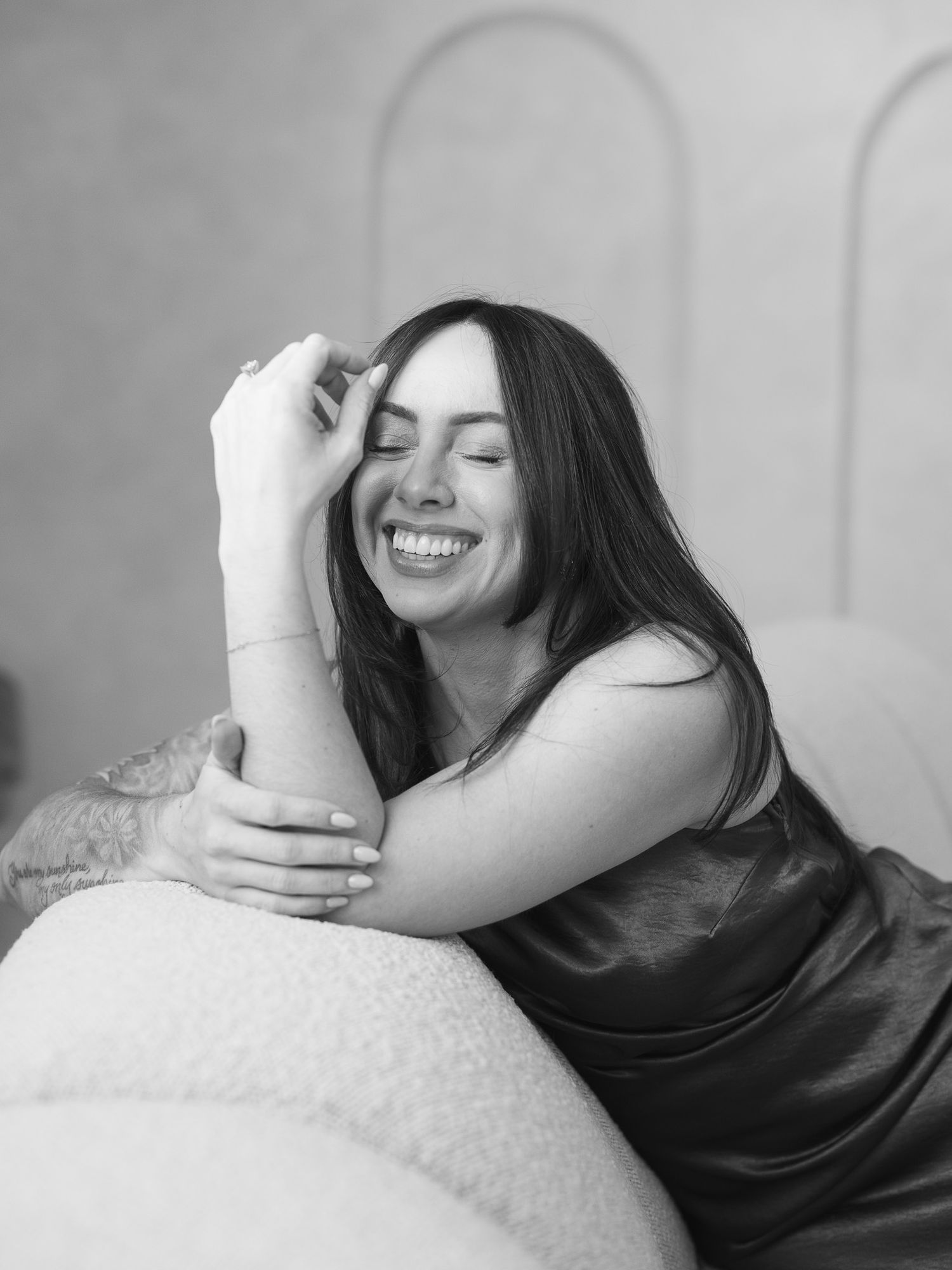 Black and white photo series showing a person lying down and laughing joyfully against a light background.