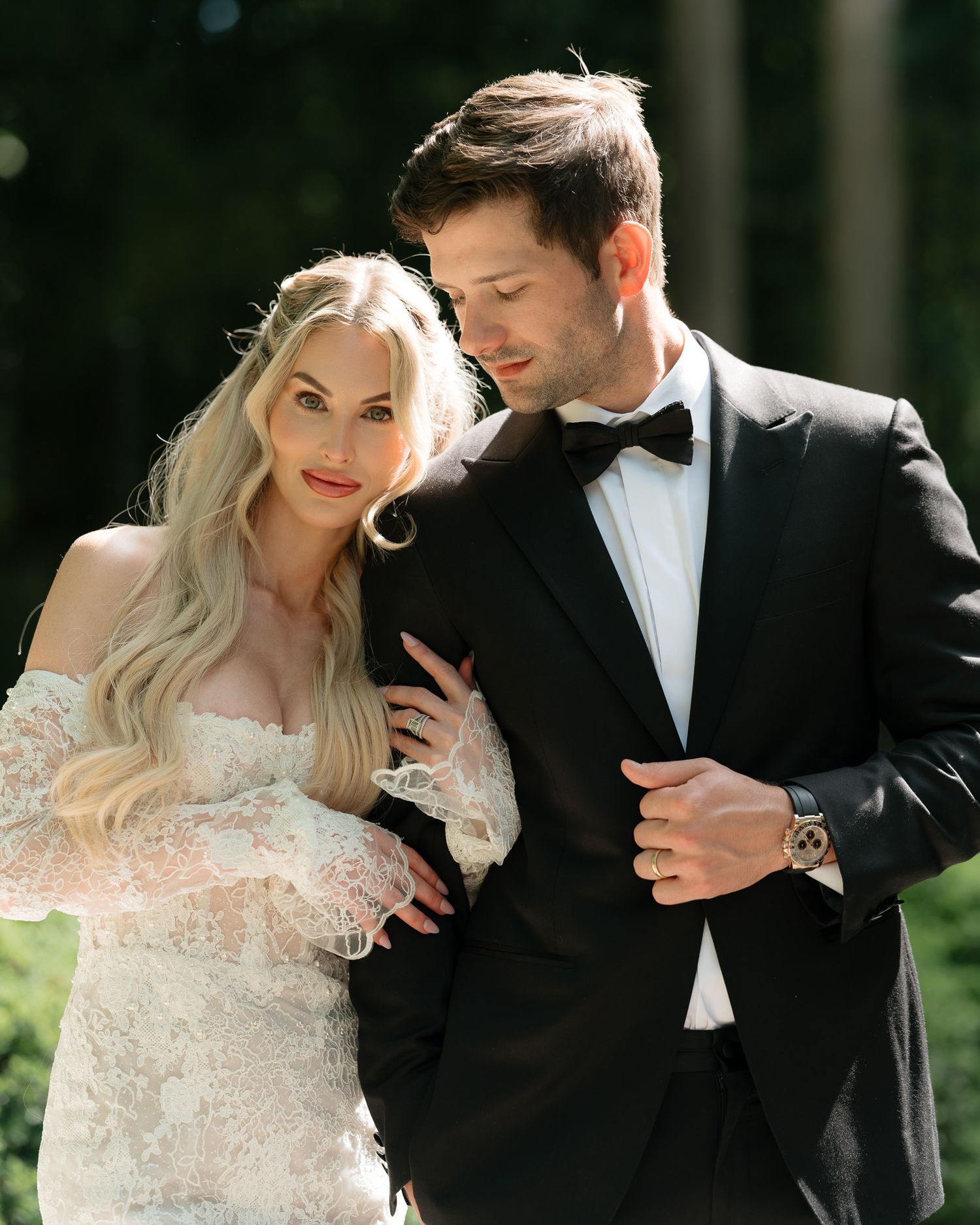 Bride and groom in wedding attire posing together outdoors.