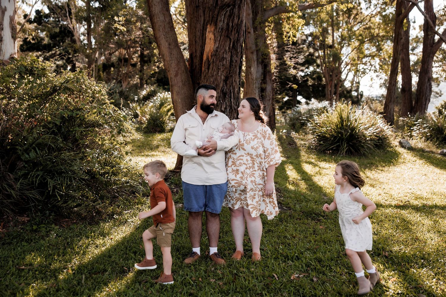 Family enjoying a sunny moment together in a garden setting with trees and natural lighting.