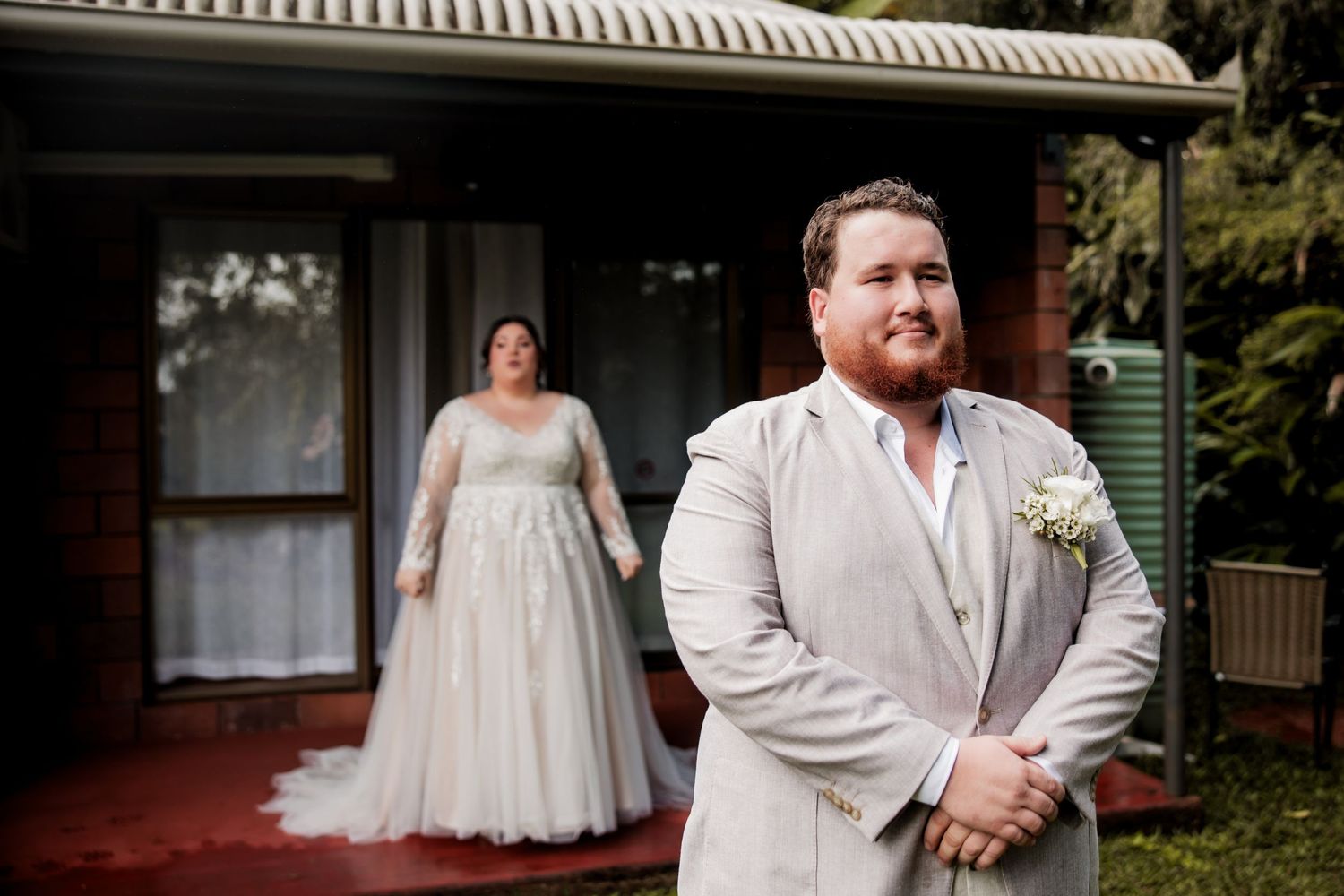 Bride and groom share their first look moment outside a rustic brick house.