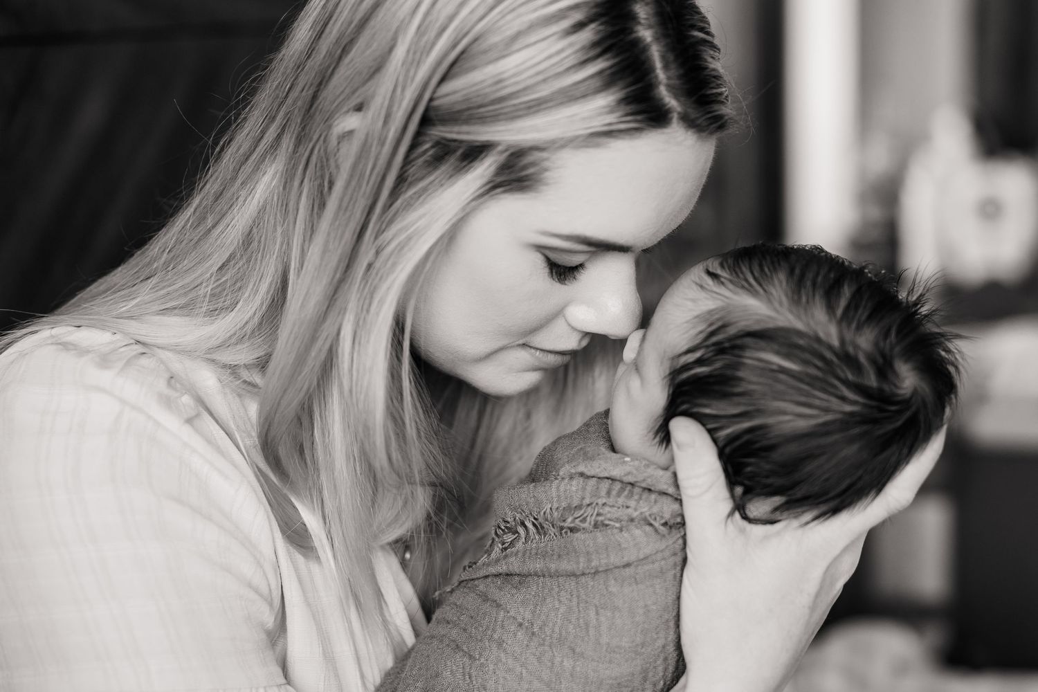 A tender moment between parent and newborn in black and white.
