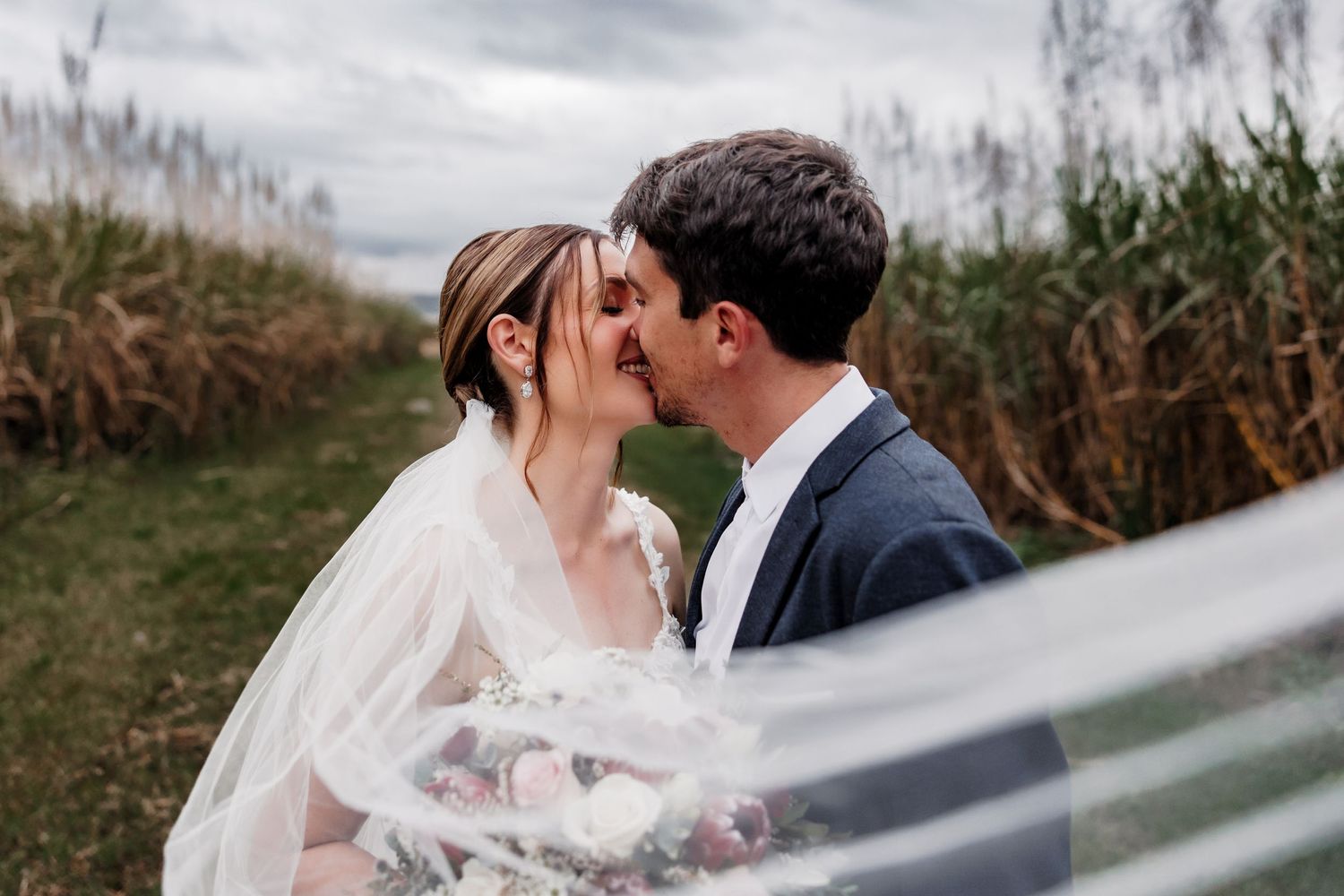 Couple embraces romantically against a scenic mountain backdrop on their wedding day.