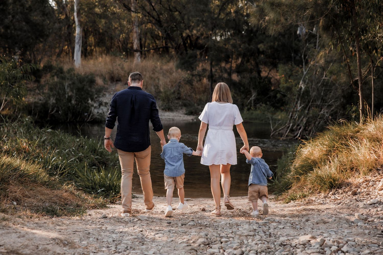 Family walking hand in hand down a rustic nature path.