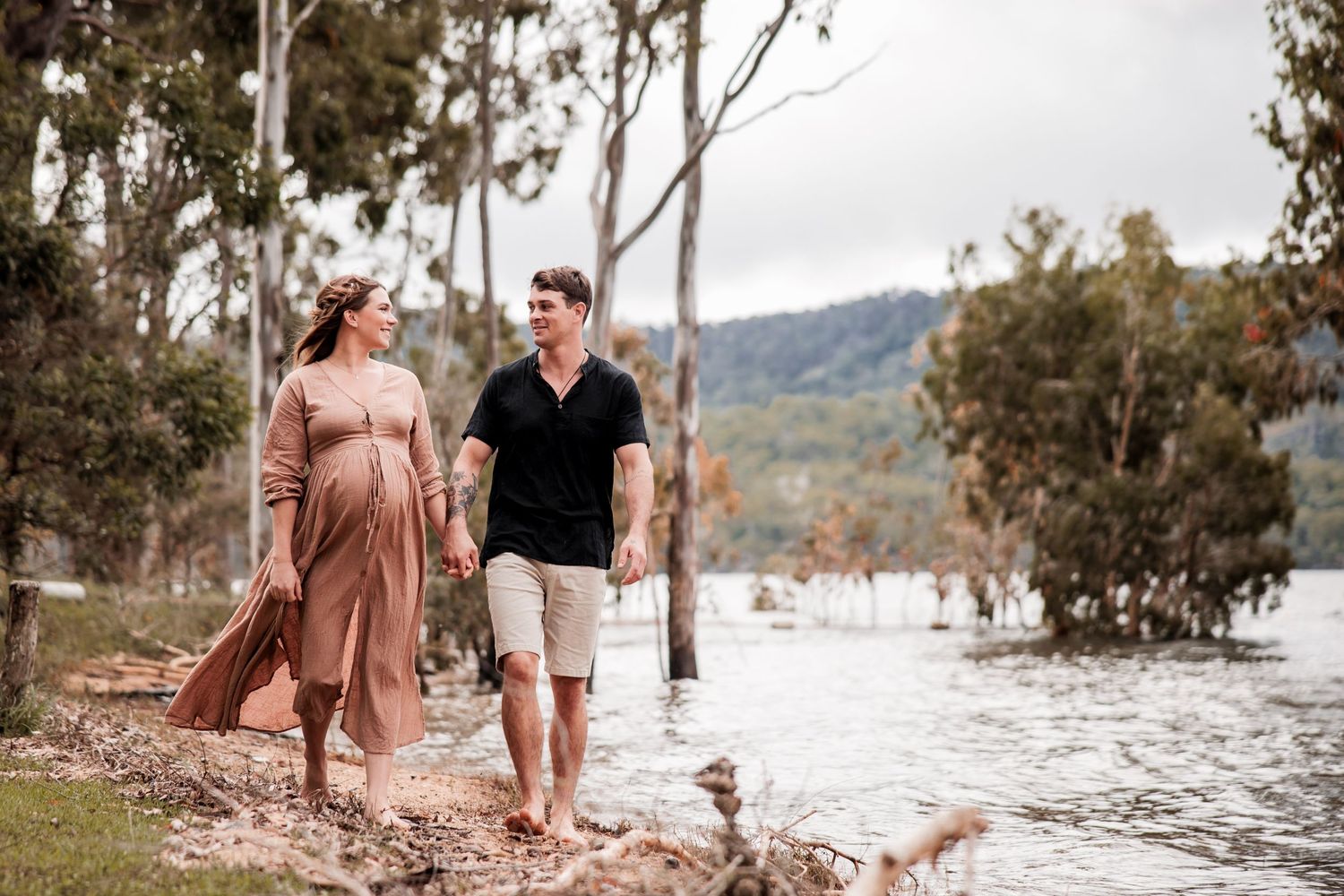Couple walking along a scenic waterfront path surrounded by eucalyptus trees.