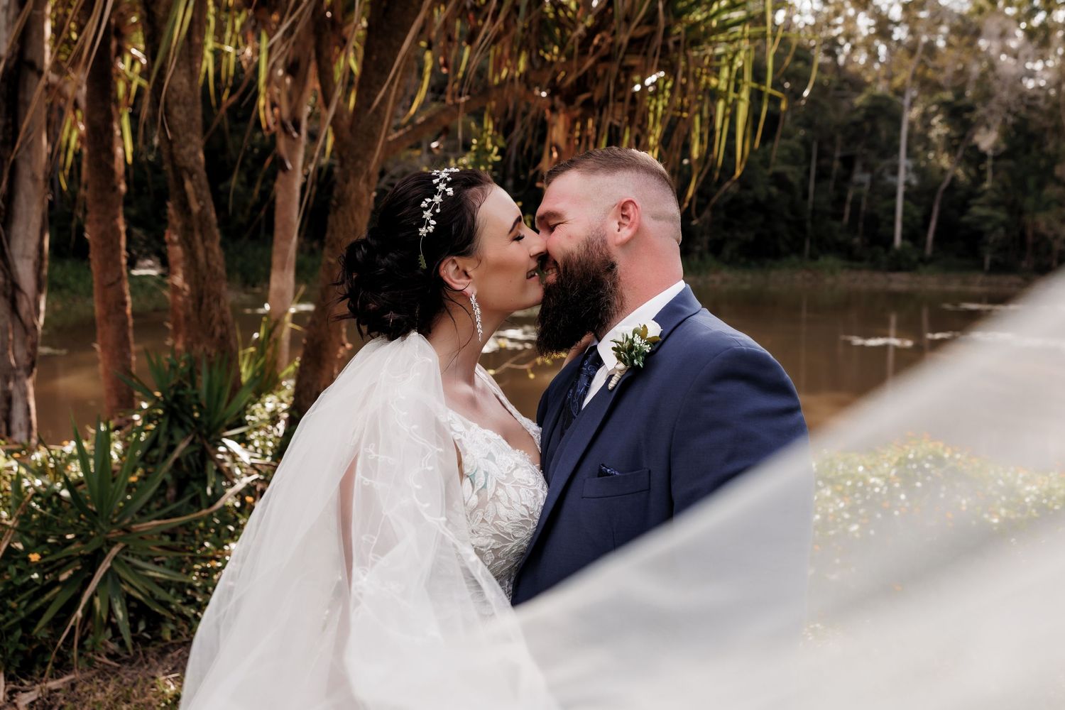 Romantic wedding couple sharing an intimate moment in a lush outdoor garden setting.