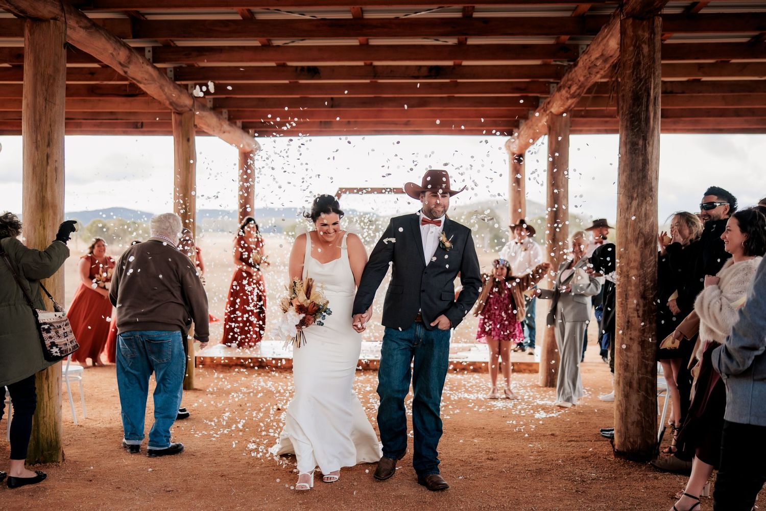 Newlyweds walking under a rustic wooden pavilion during their wedding ceremony.