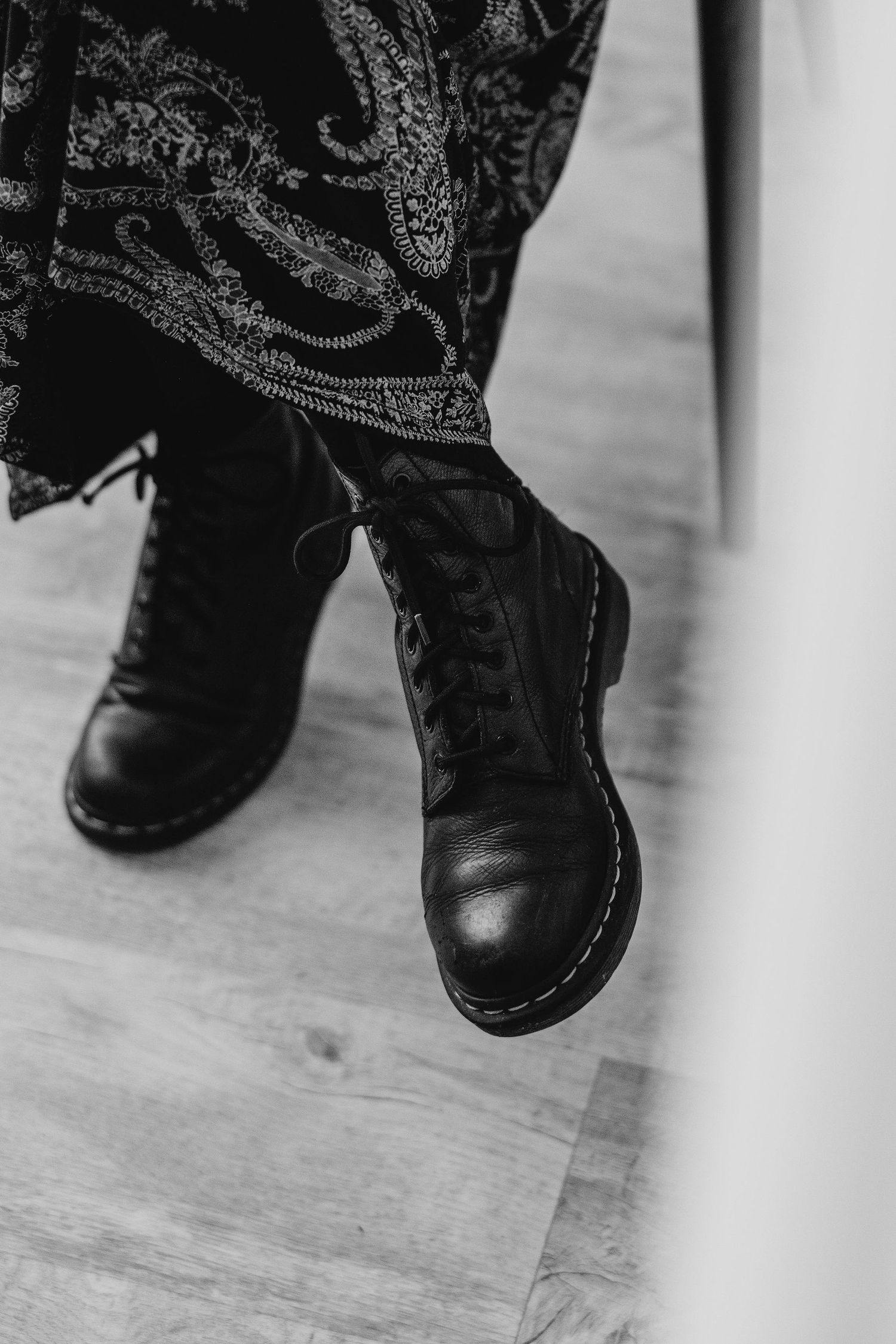 Close-up black and white photo of boots on a wooden floor.