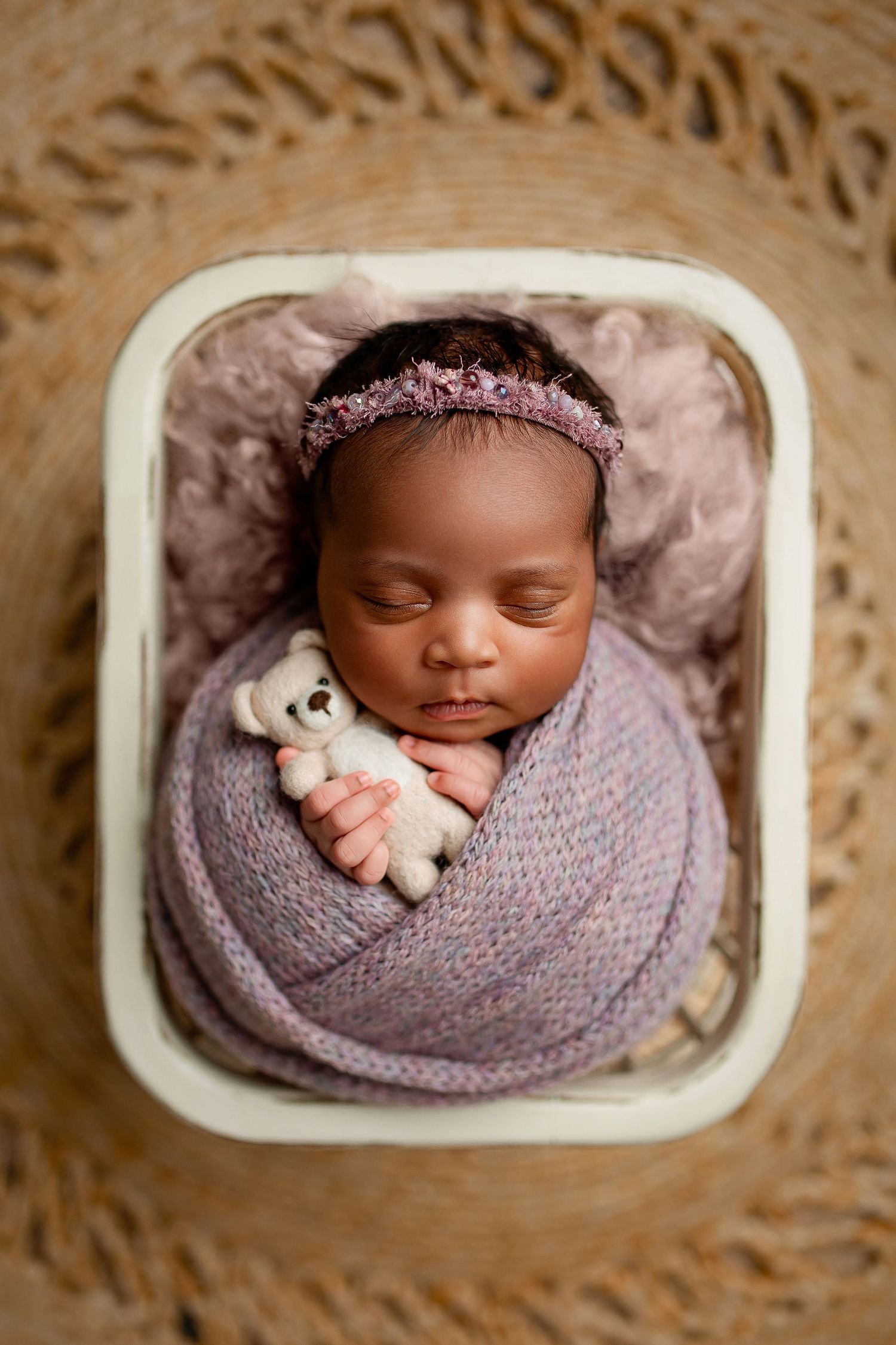 Newborn baby girl wrapped in purple knit with teddy bear in vintage basket at Flowertown Photography newborn studio in Summerville SC