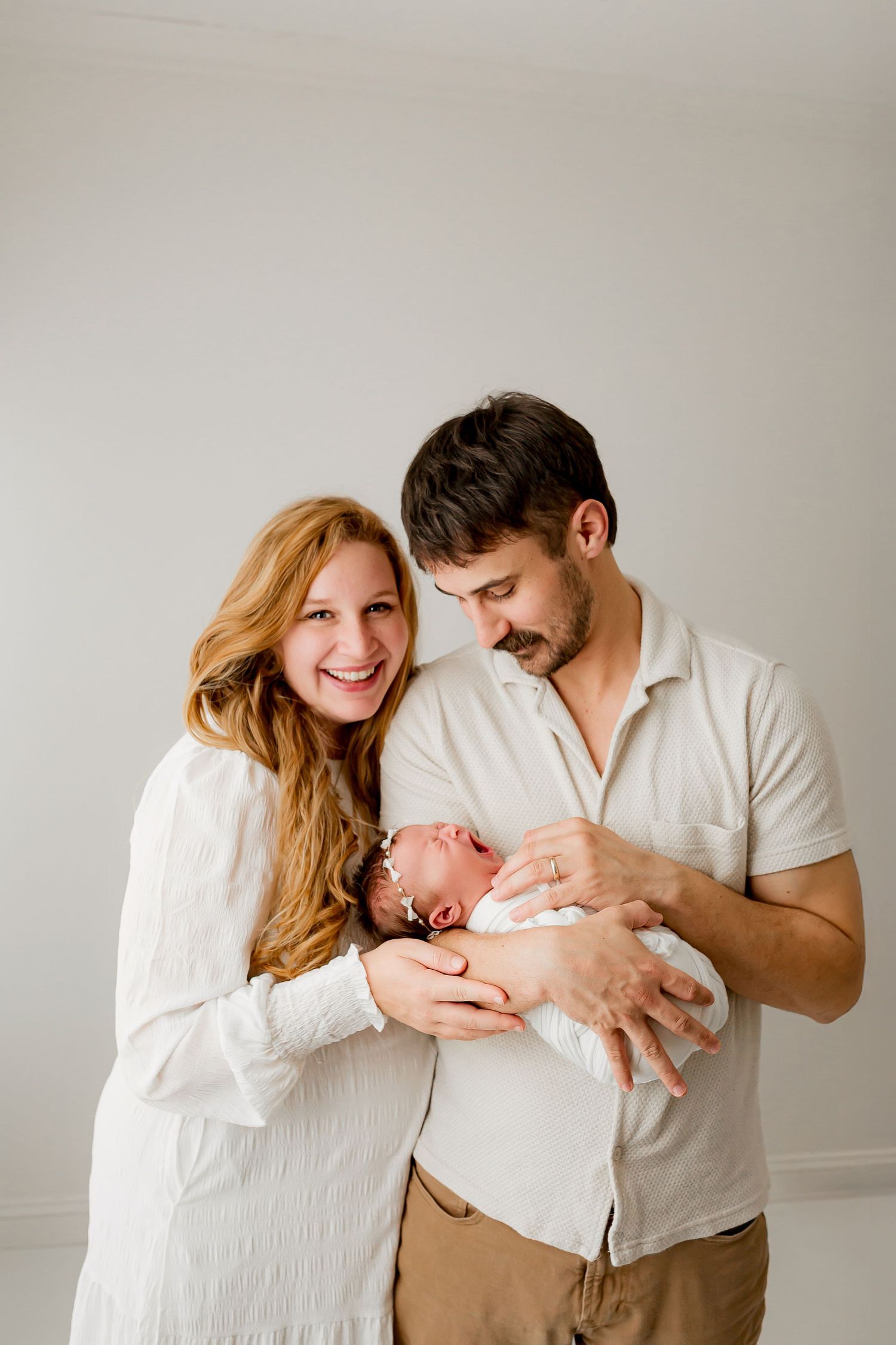 Happy parents holding newborn baby during portrait session at Flowertown Photography studio in Summerville SC