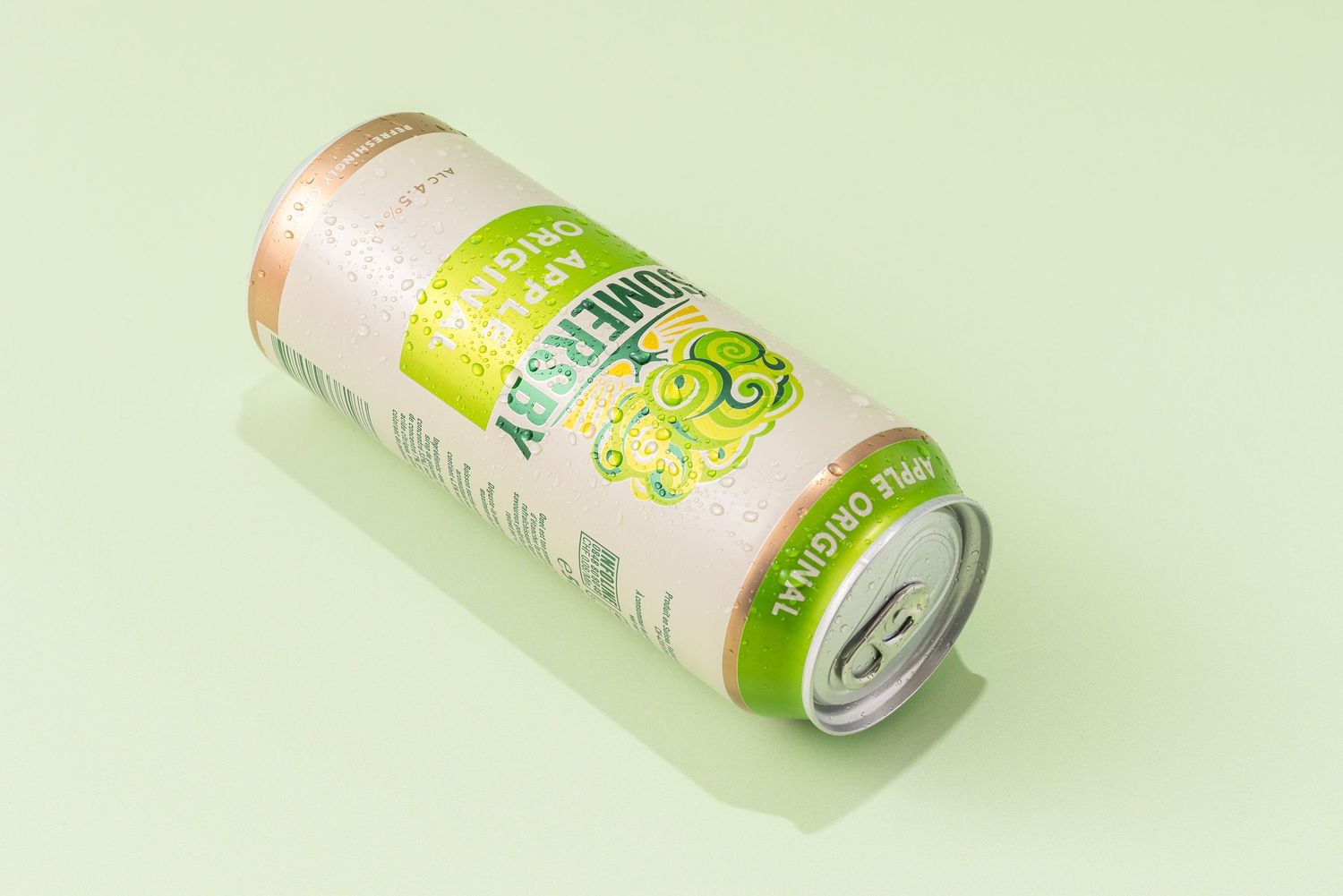 A white and green aluminum beverage can with citrus design elements lying on a light green background.