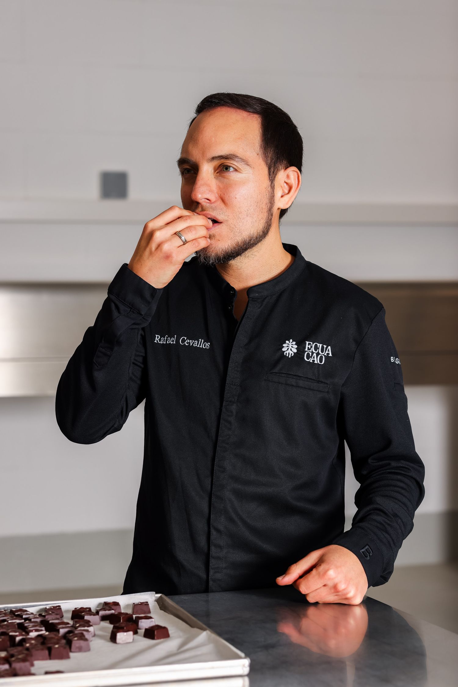 Chef in black uniform examining food at a tasting session.