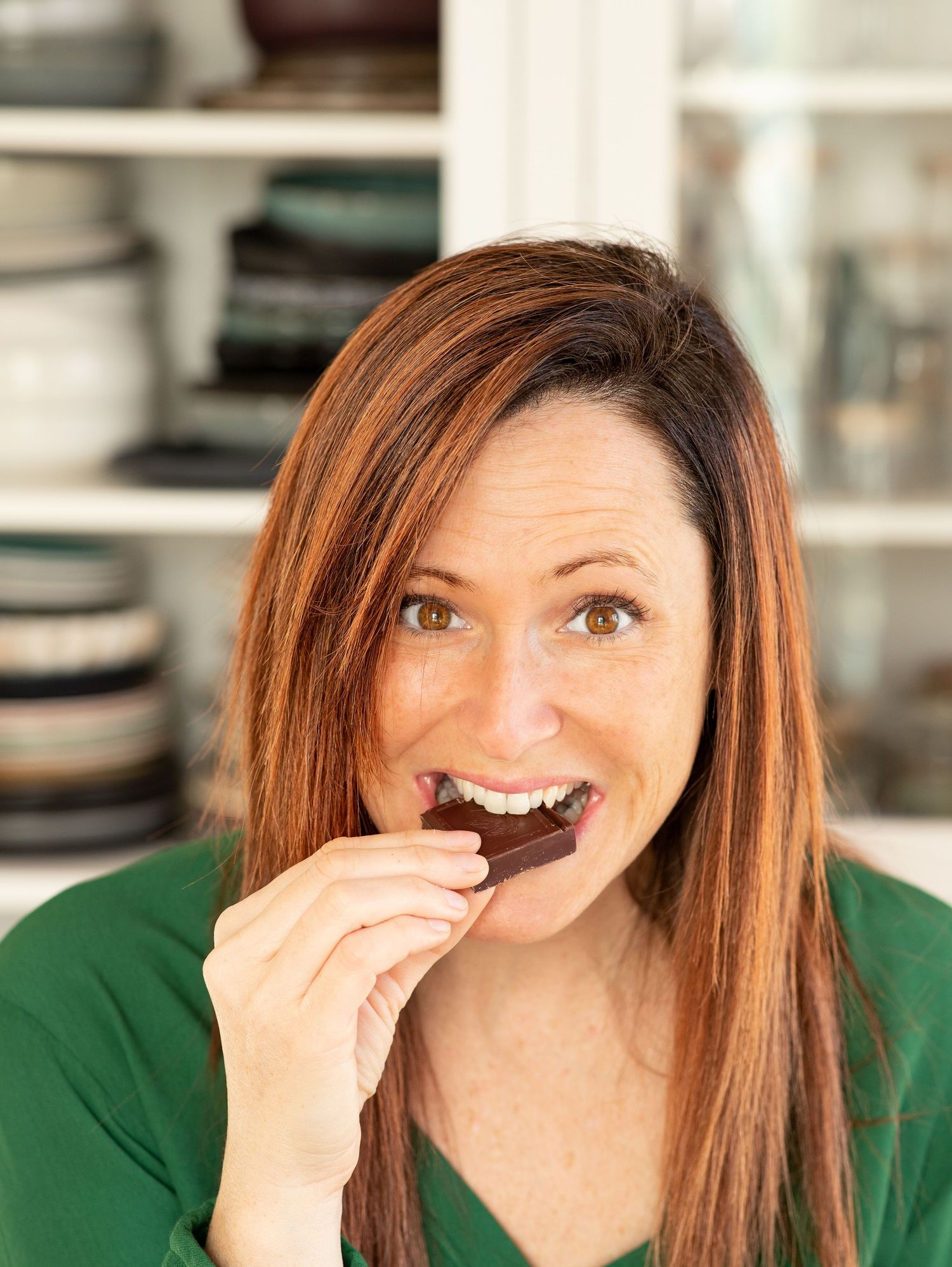 Person in green sweater taking bites of chocolate and showing expressions of enjoyment in a photo sequence.