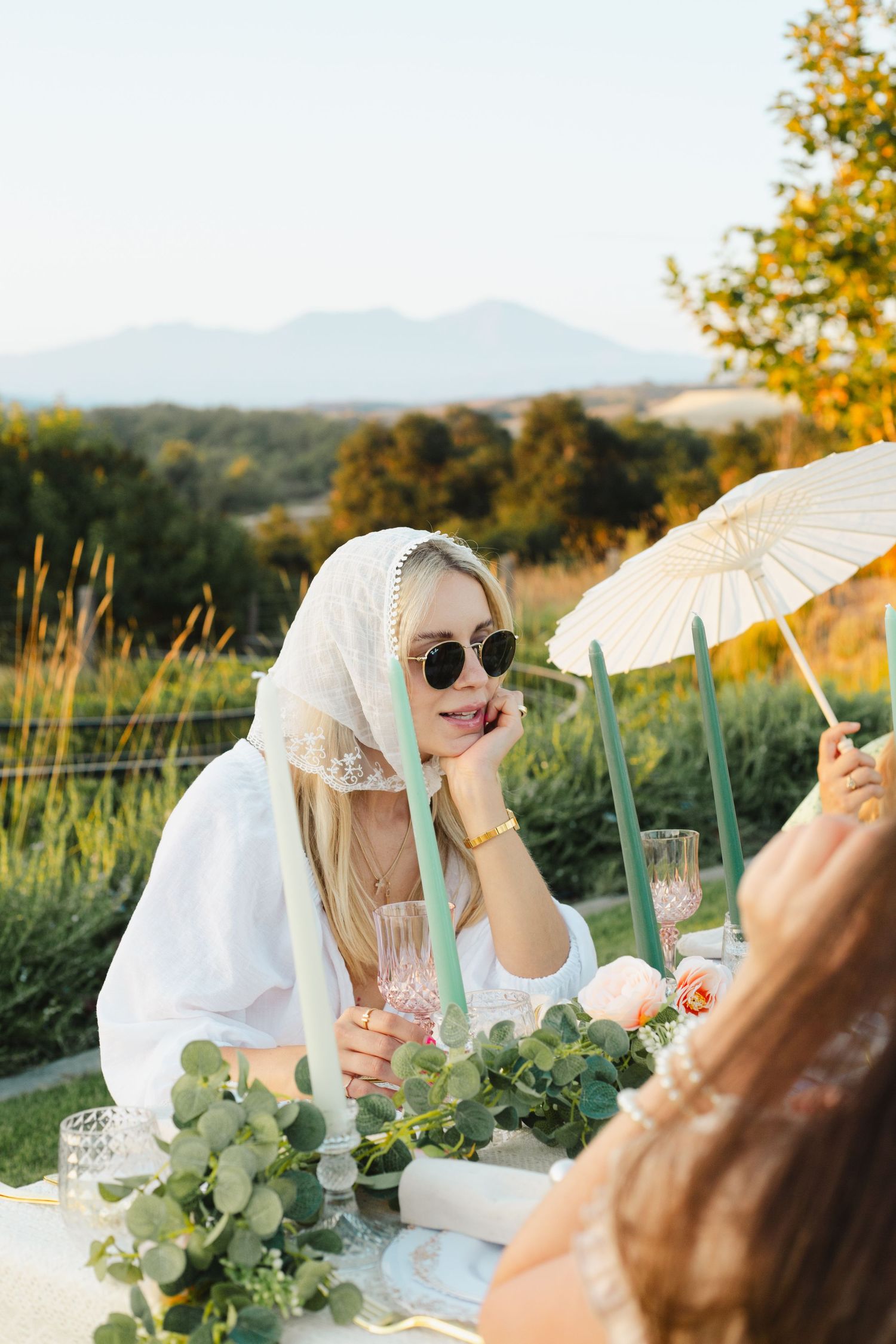 Outdoor dining scene with parasol and mountain views during sunset.
