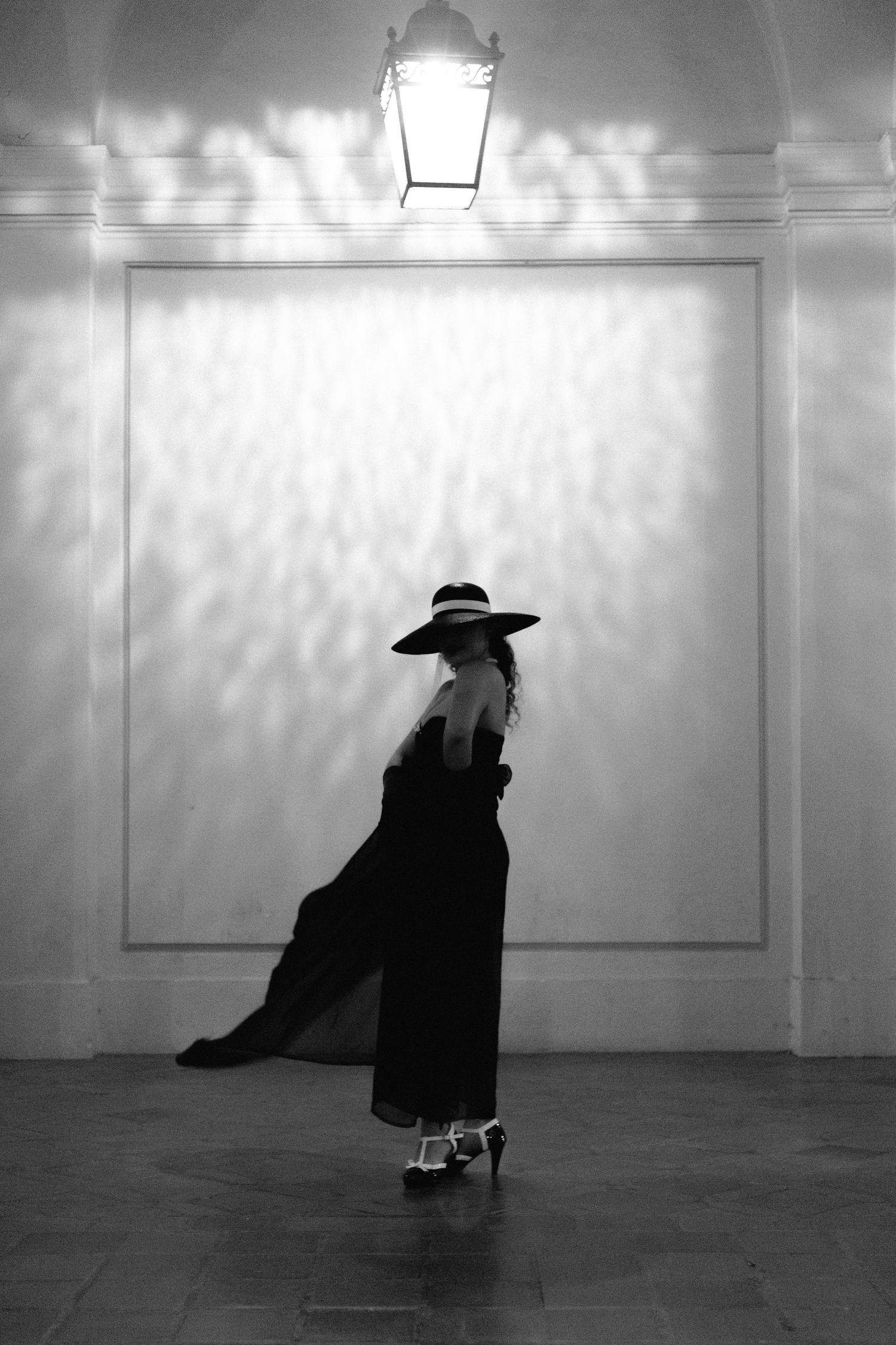 Dramatic silhouette sequence against white wall with theatrical lighting effects.