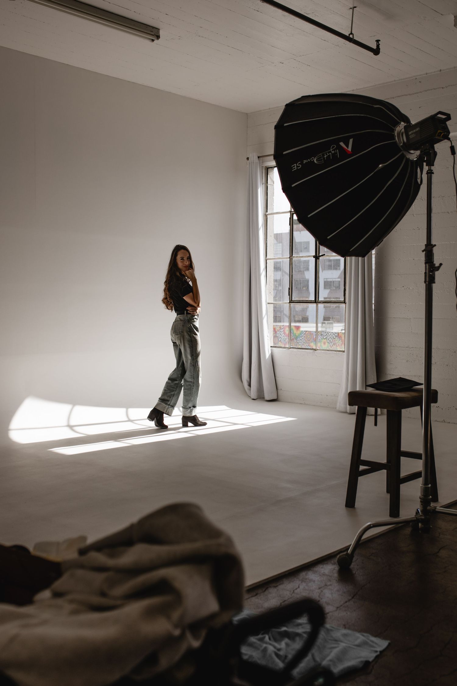 Photography studio setup with lighting equipment and shadows cast across an empty white room.