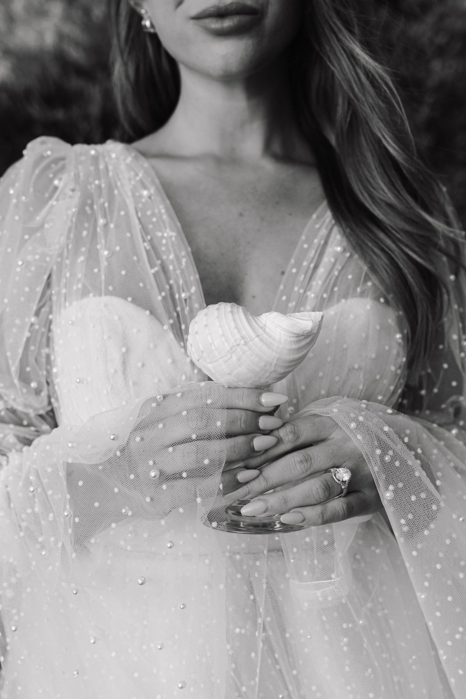 Black and white photo of a romantic wedding dress with sheer polka dot sleeves and a sweetheart neckline.