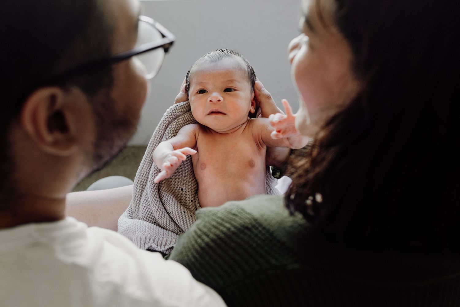 A series of intimate black and white photographs showing tender family moments with a baby.
