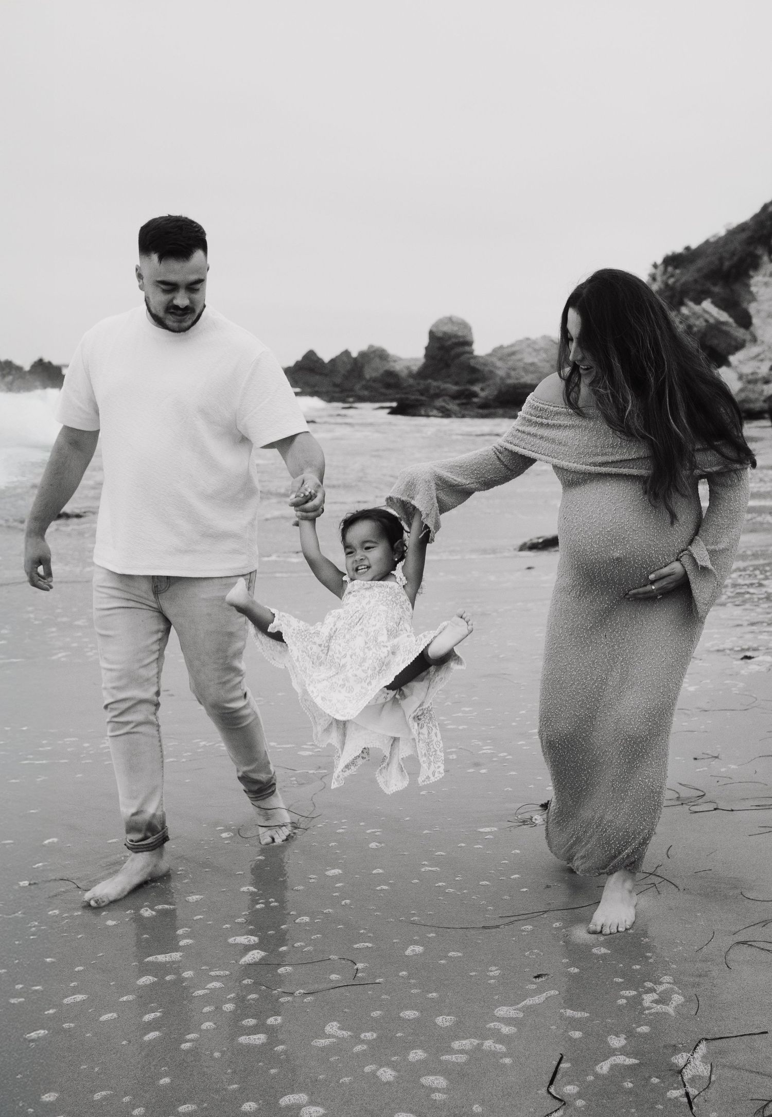 A sequence of black and white photos showing people walking and playing on a beach in matching white outfits.