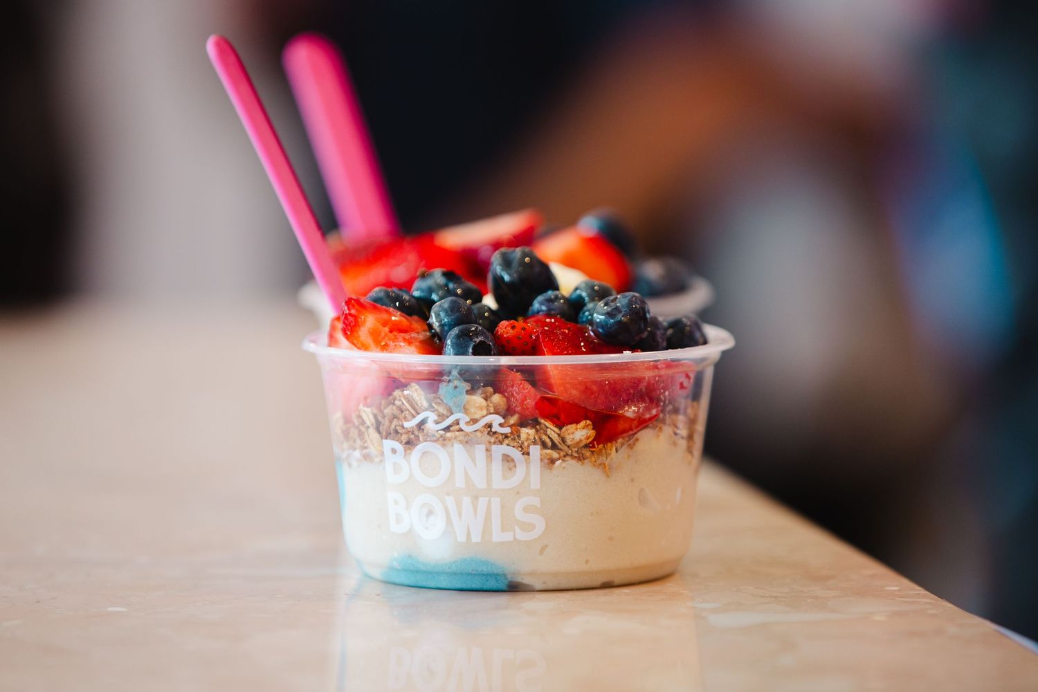 Row of colorful acai bowls topped with fresh berries and fruits on wooden surface.