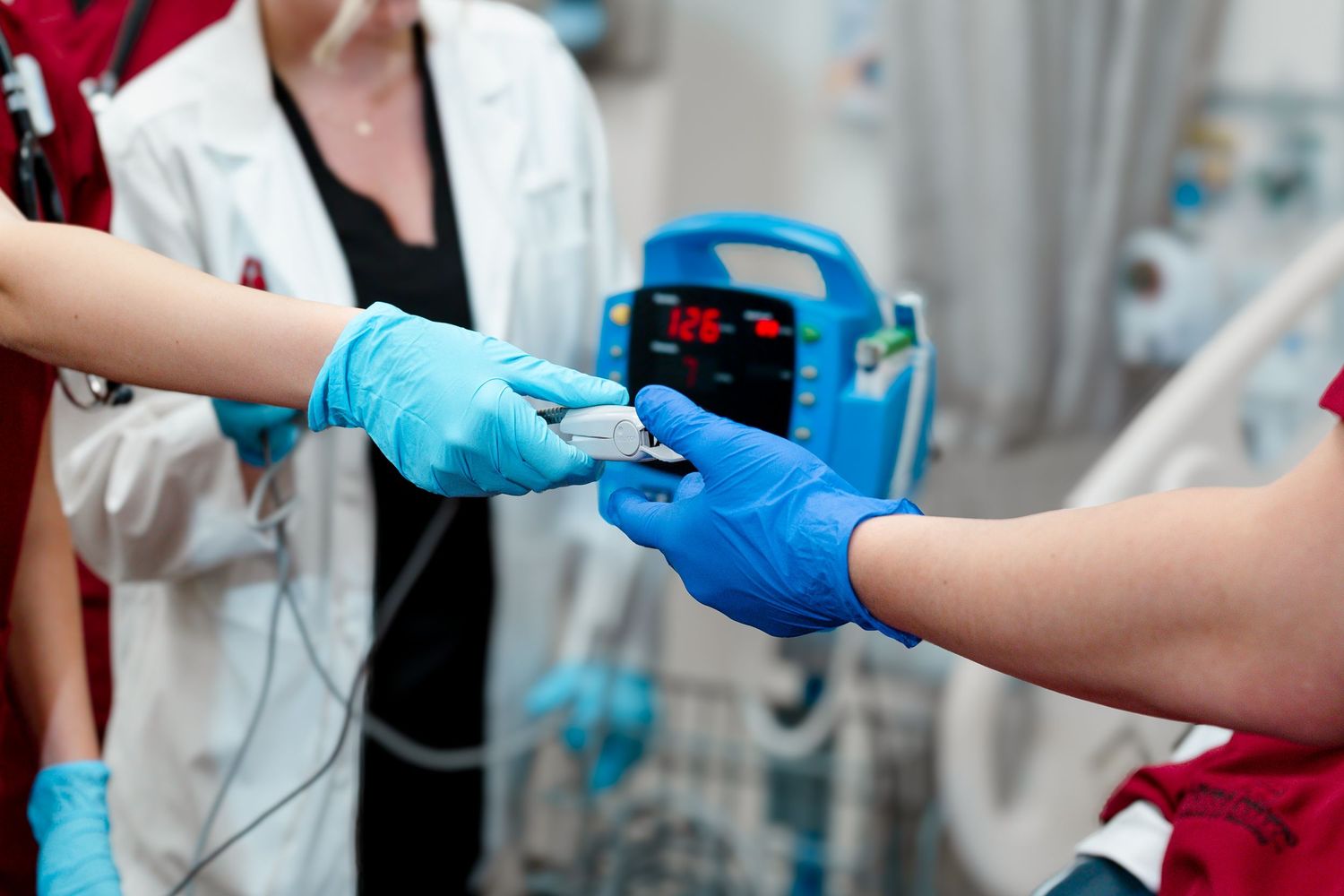 Healthcare worker in blue gloves draws blood from patient's arm while wearing protective medical equipment.