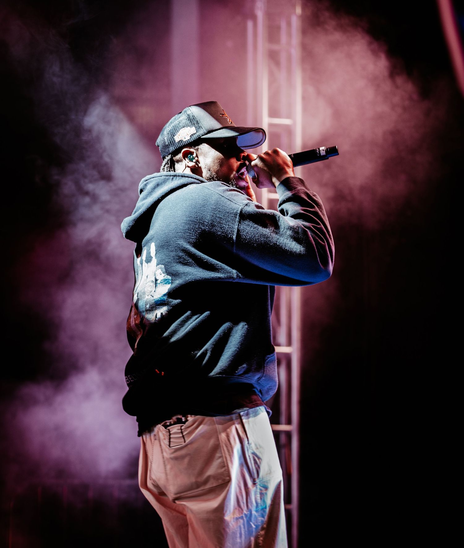 A dancer performs an energetic hip-hop move against a dark background with purple smoke effects.
