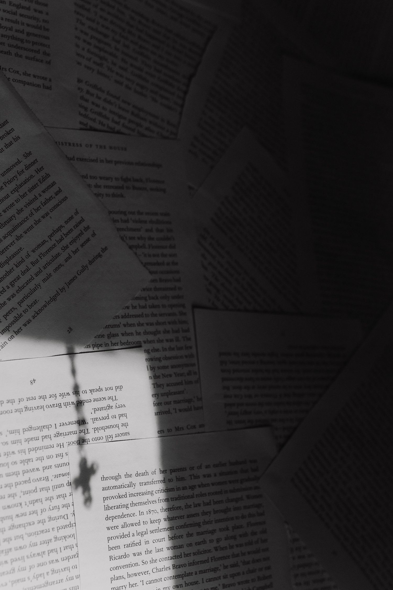 Moody black and white image of scattered paper documents with text visible.