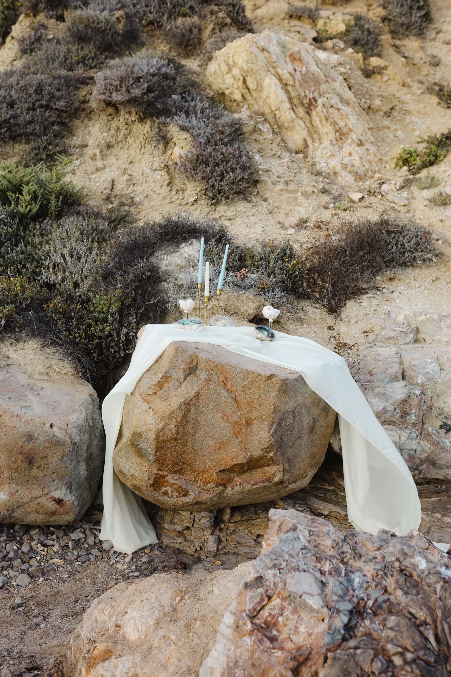 A sequence of rocks covered with white plastic or fabric material along a rocky hillside terrain.