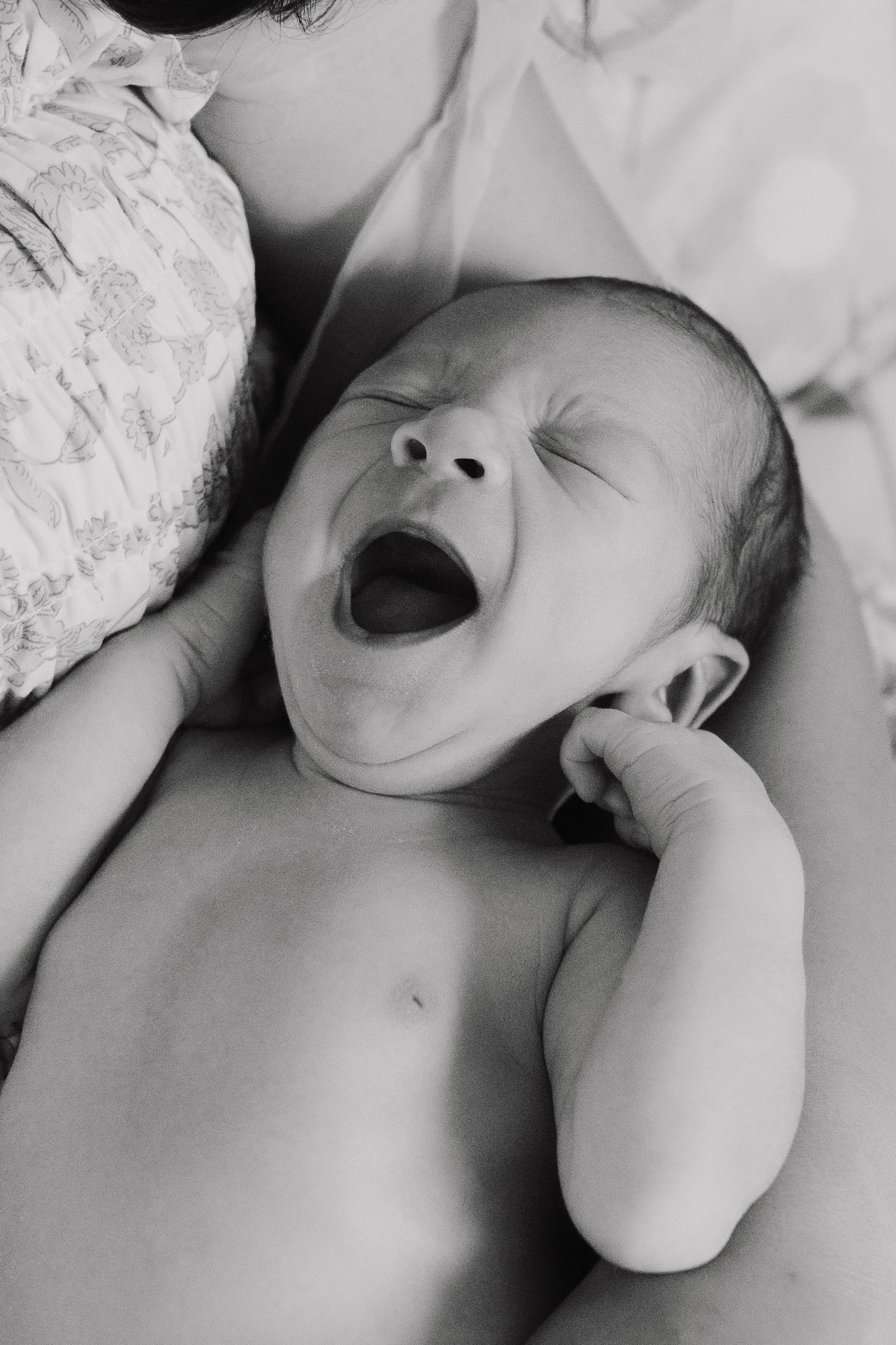 Black and white photo series showing a sleeping newborn baby in different peaceful poses on white bedding.
