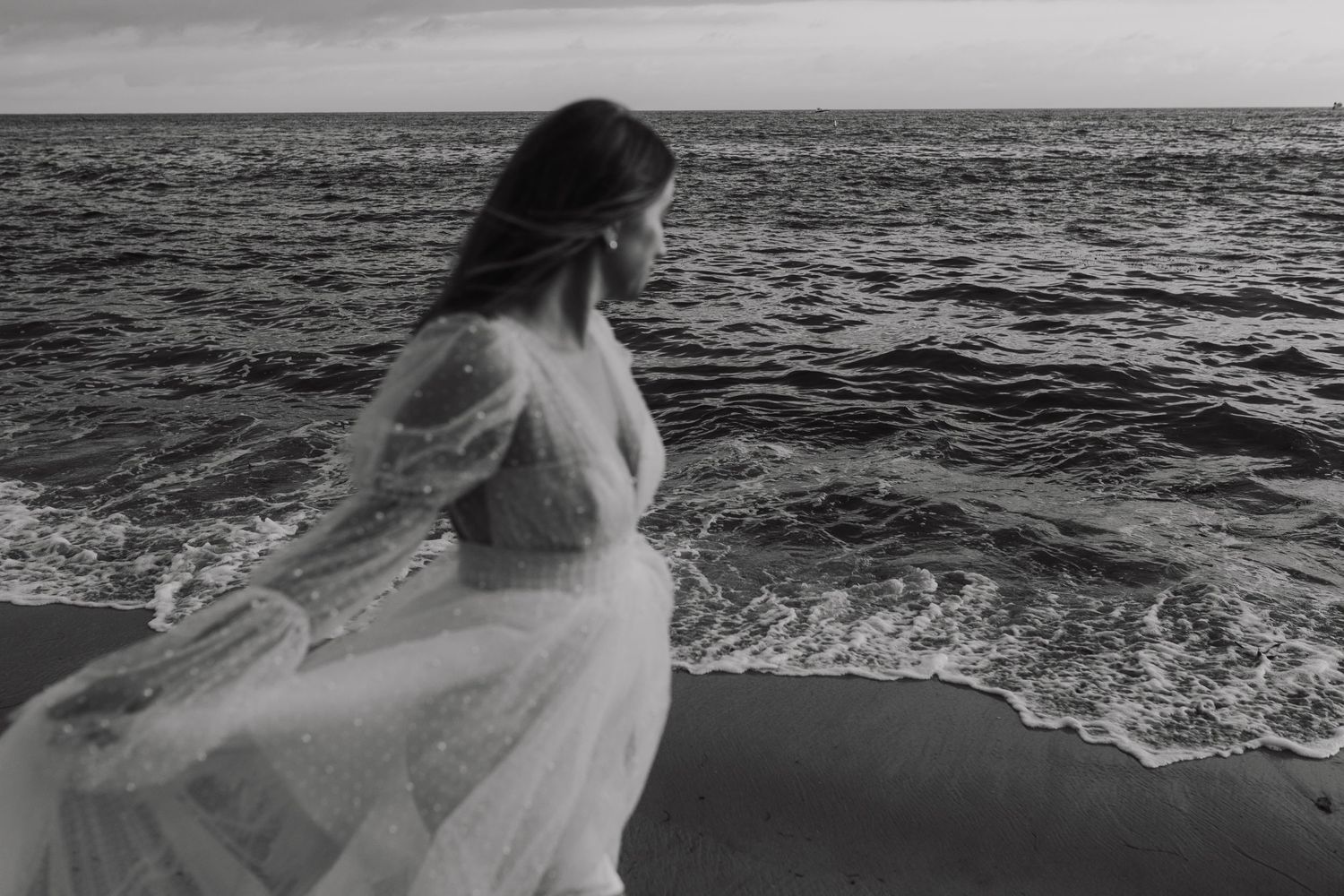 A dramatic black and white photo series shows a figure with flowing fabric on a rocky beach at sunset.