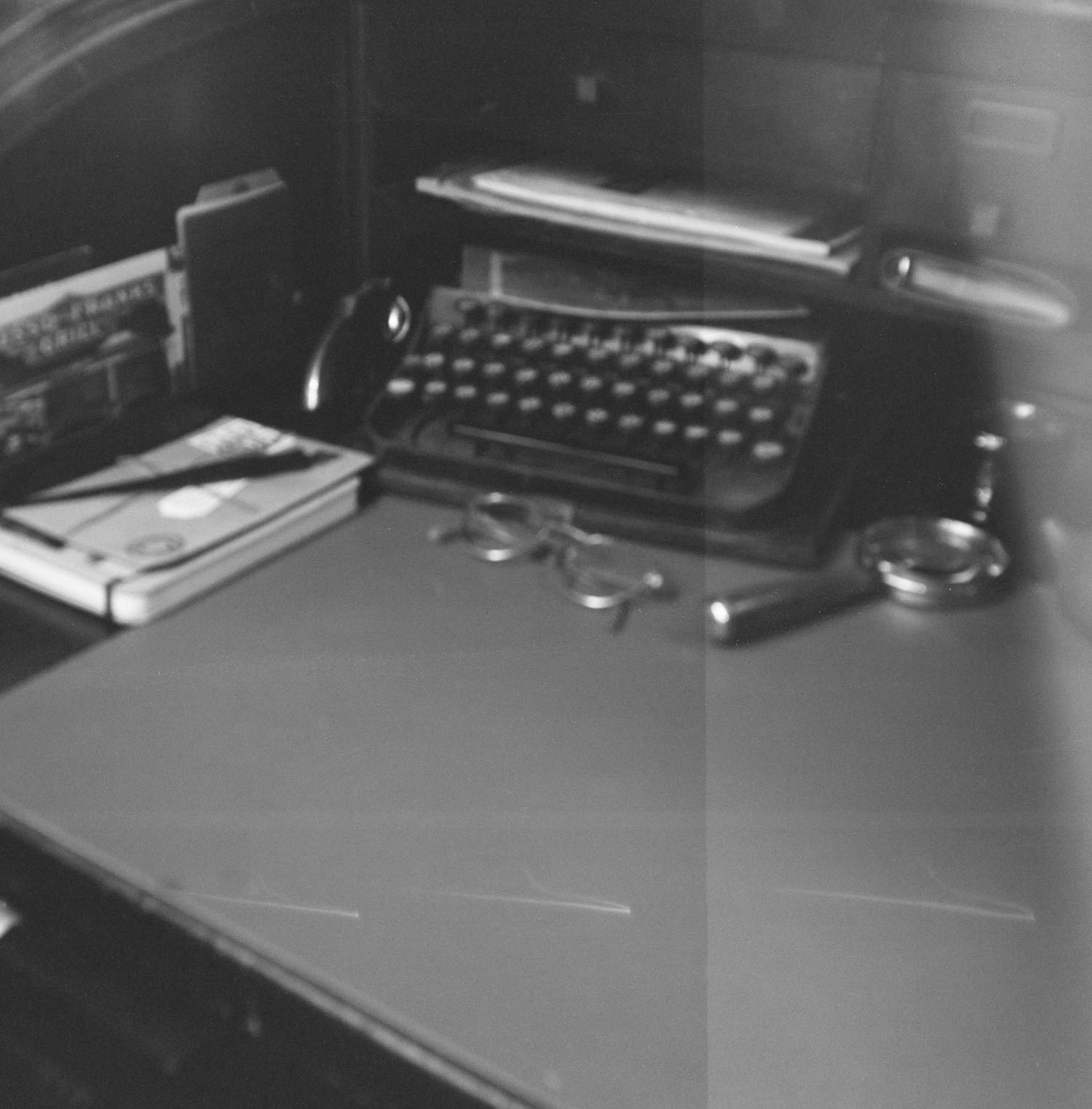 Vintage typewriters and office supplies arranged on a desk in monochrome.