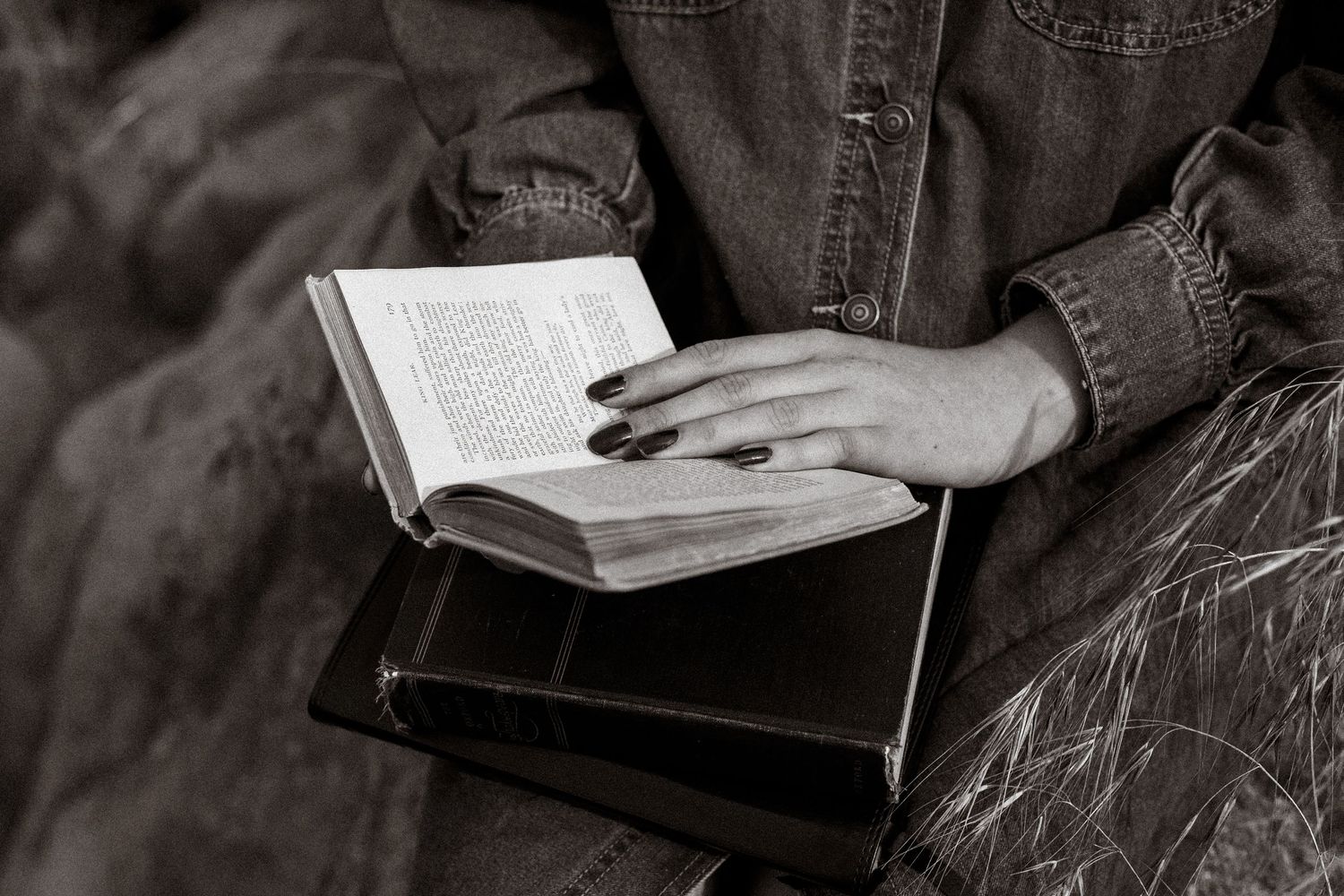 A person's hands hold open a hardcover book against a dark textured background.