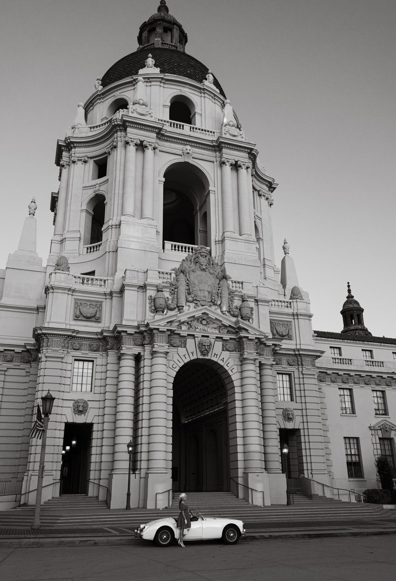 Majestic white church facade with classic car parked in front, captured in black and white.