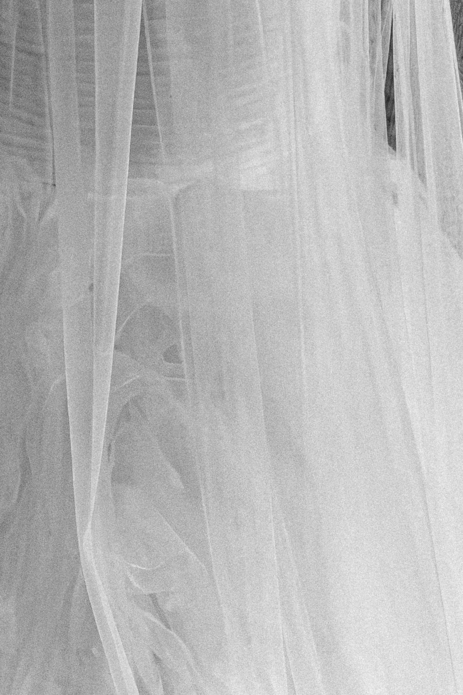 Delicate white bridal veil fabric with soft flowing layers and subtle texture in black and white photography.