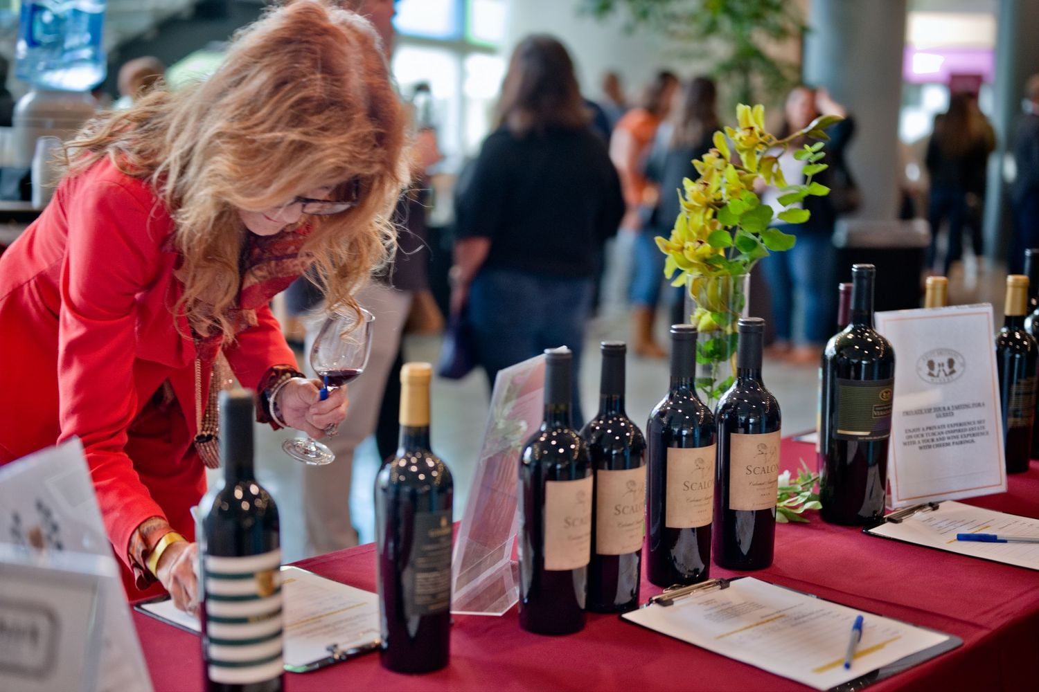 Wine tasting event showing multiple bottles and attendees evaluating different vintages on a long table.