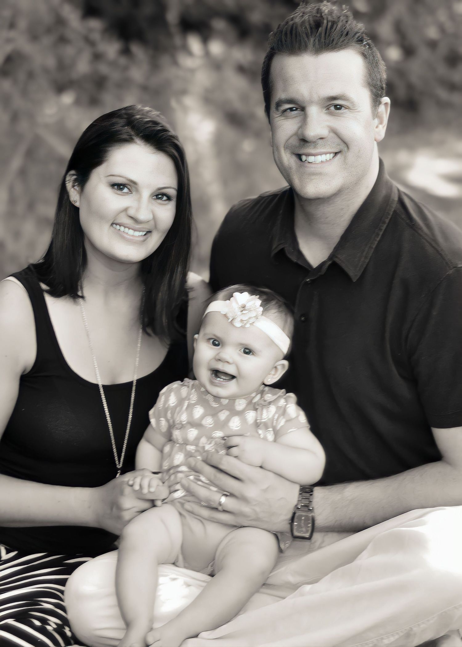 Black and white photo of a joyful couple with their baby in outdoor portrait. Napa, CA