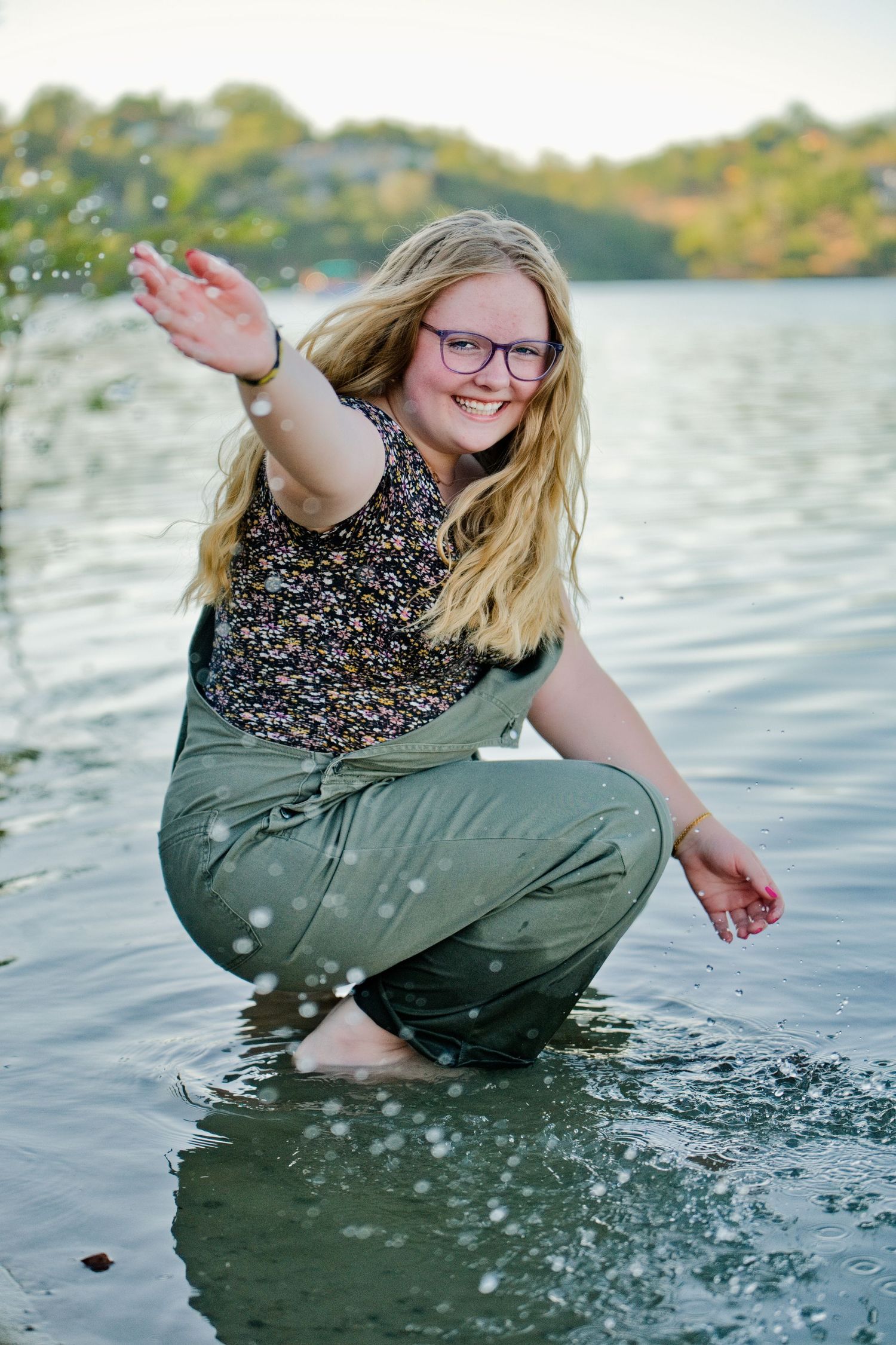 A series of four photos showing someone splashing and playing in water by a lake on a sunny afternoon.