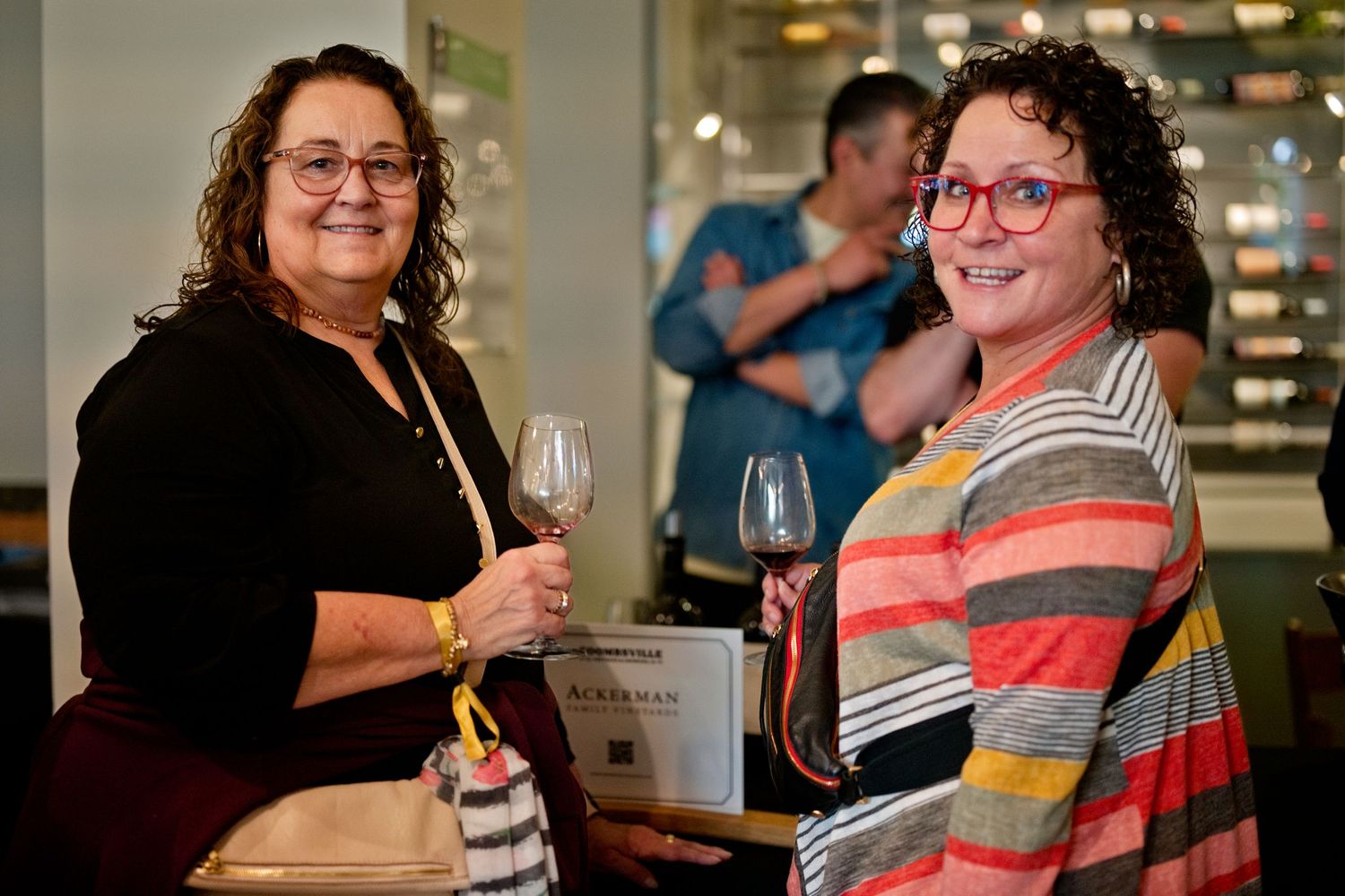 Two people enjoying wine and conversation at an indoor social gathering with glassware and smiles.