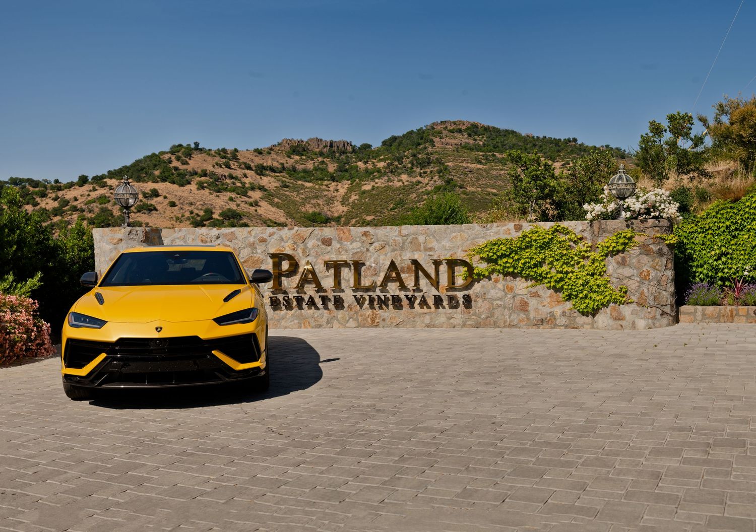 A yellow Lamborghini supercar parked at Patland Estate Winery, framed by the scenic Soda Canyon hills in Napa Valley.
