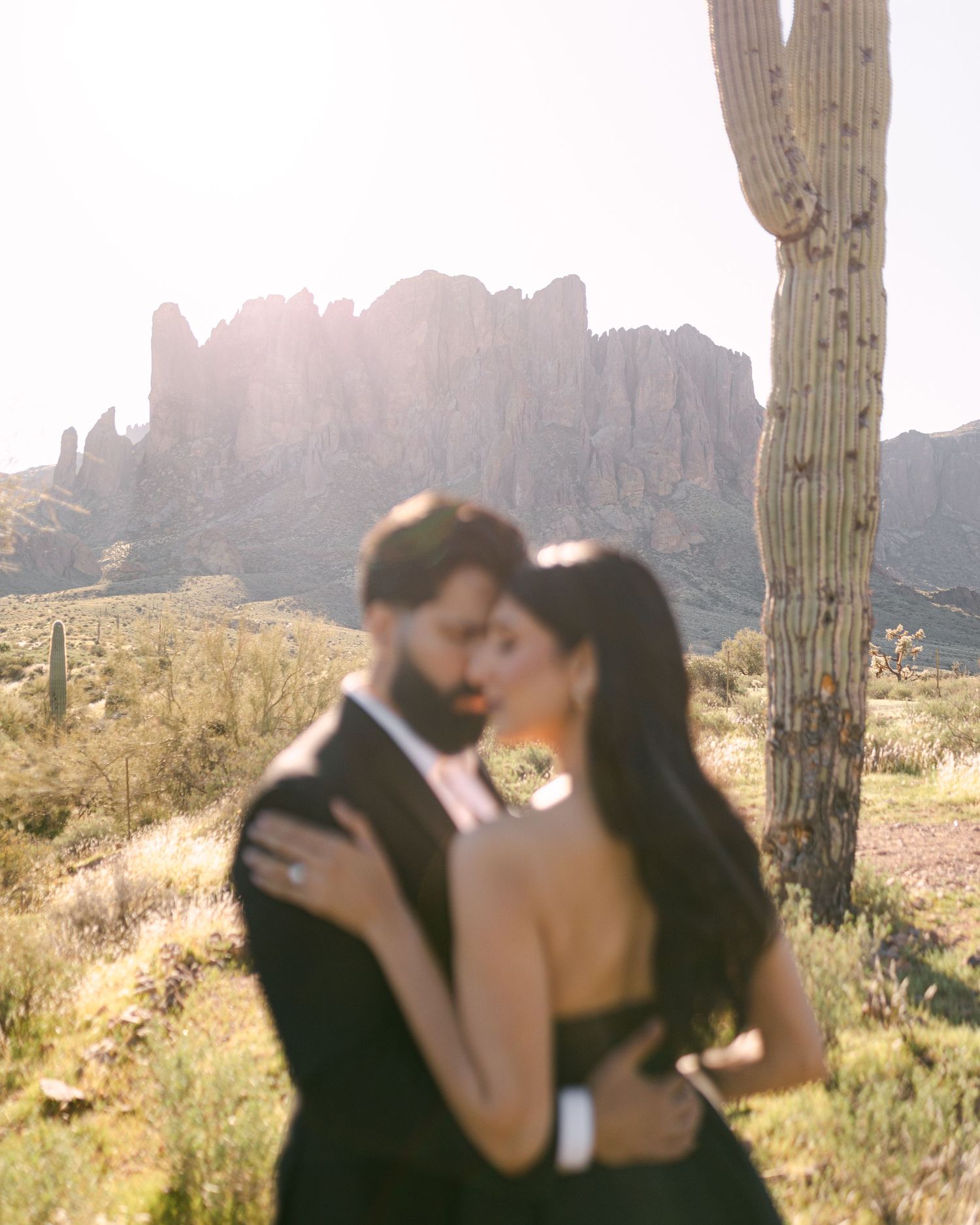 Romantic desert engagement photo with Superstition Mountains and saguaro cactus backdrop.