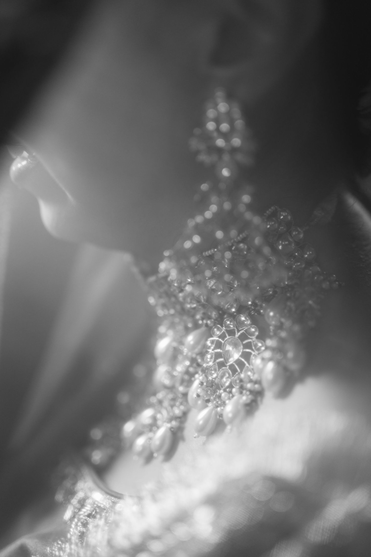 Close-up black and white macro photograph of sparkling diamond jewelry with soft bokeh effect.