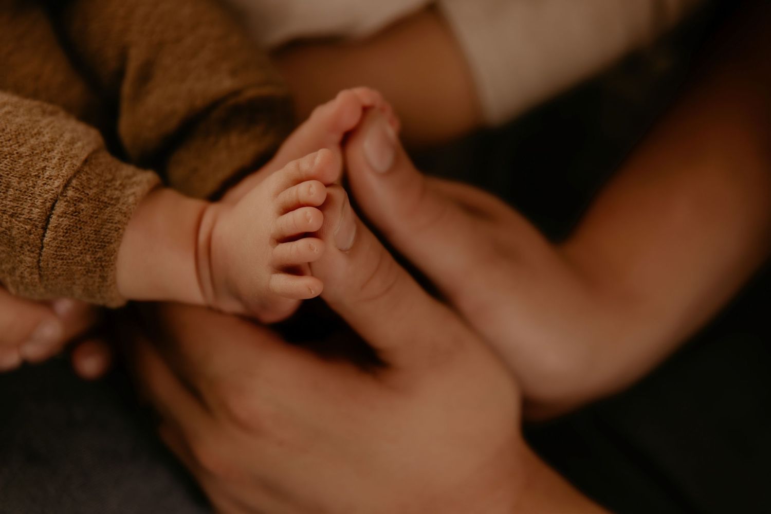 Close-up of a parent gently holding a newborn baby's tiny feet, capturing a tender bonding moment.